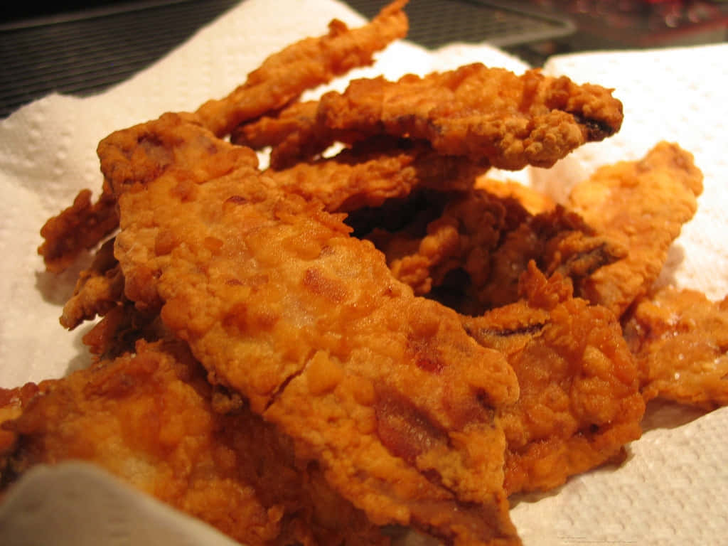 Deep Fried 桌布 壁紙 — 金黃酥脆的炸魚條高高堆放在帶有紋理表面的白色紙巾上。