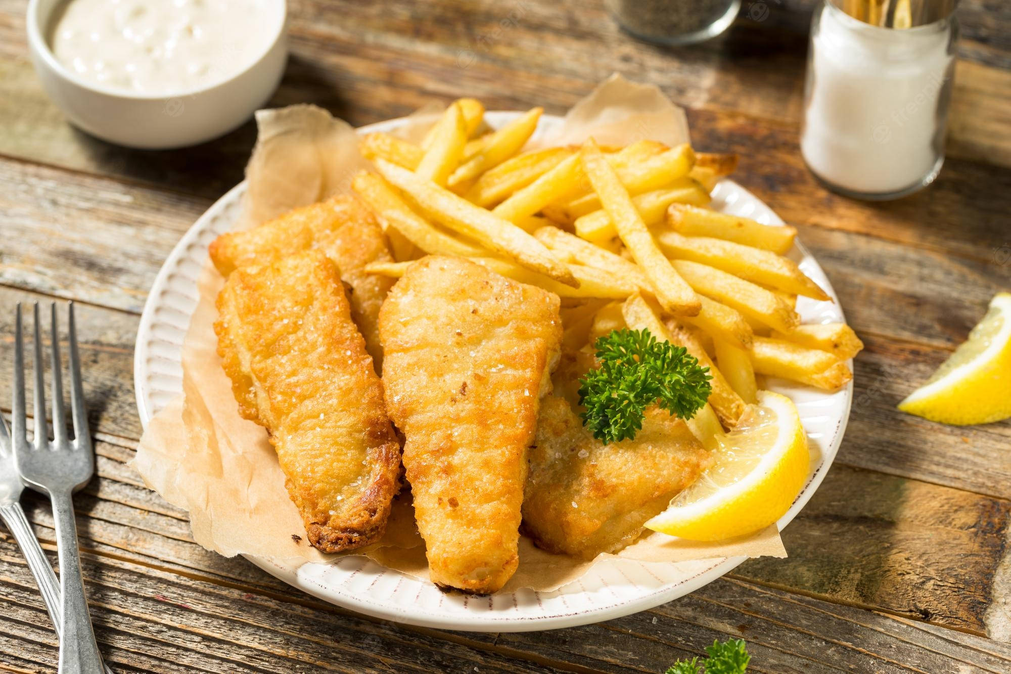 Food Photography 桌布 壁紙 — 金黃酥脆的炸魚薯條，搭配檸檬角和塔塔醬，擺放在質樸的木桌上。