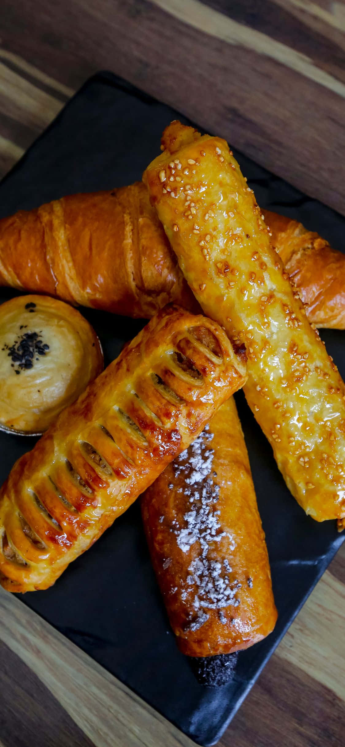 Pastry 桌布 壁紙 — 金黃酥脆的糕點，撒上芝麻和糖粉，放在木質表面上的黑色石板之上。