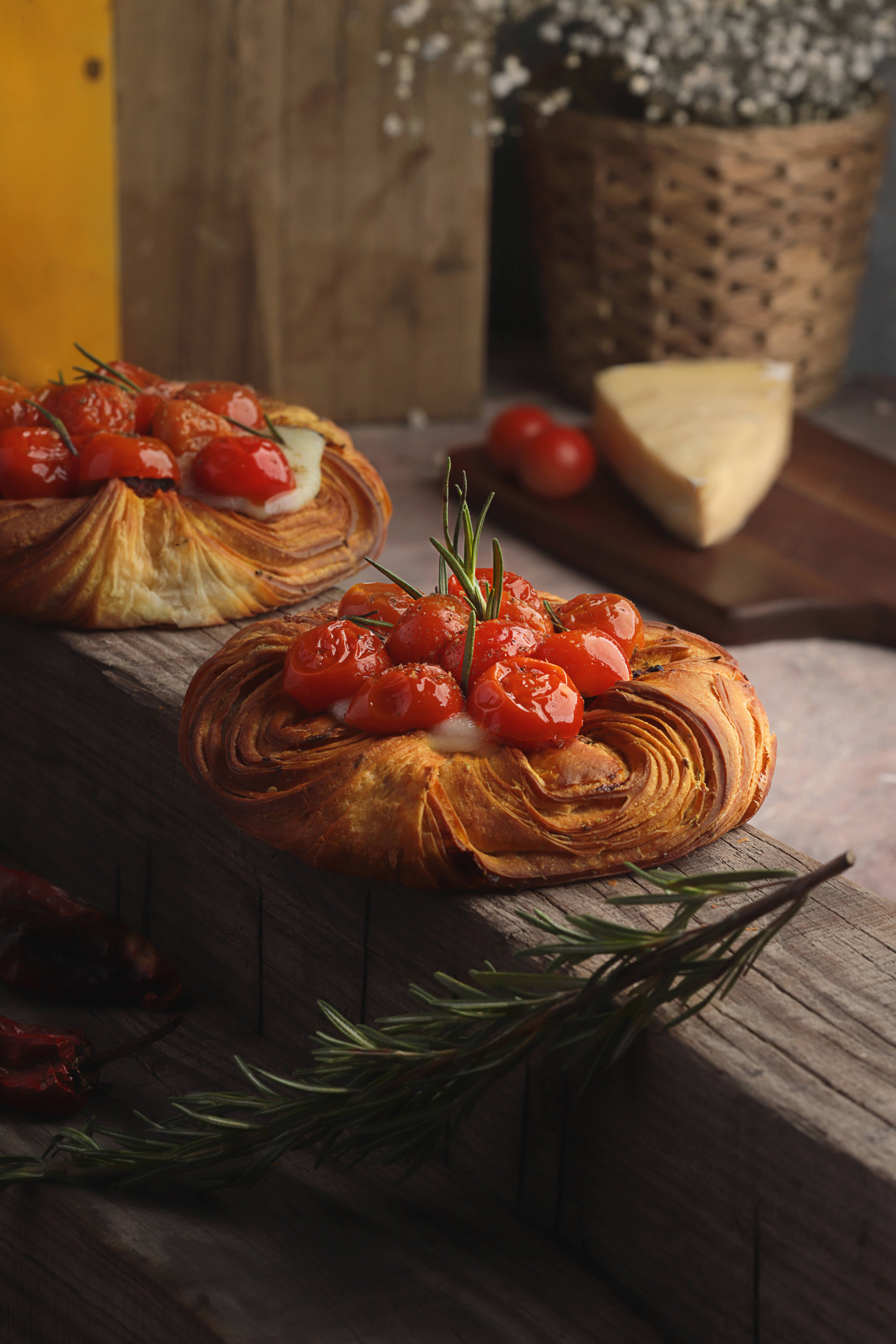 Pastries 桌布 壁紙 — 金黃酥脆的糕點上放有烤櫻桃番茄和迷迭香，置於質樸的木質表面上。