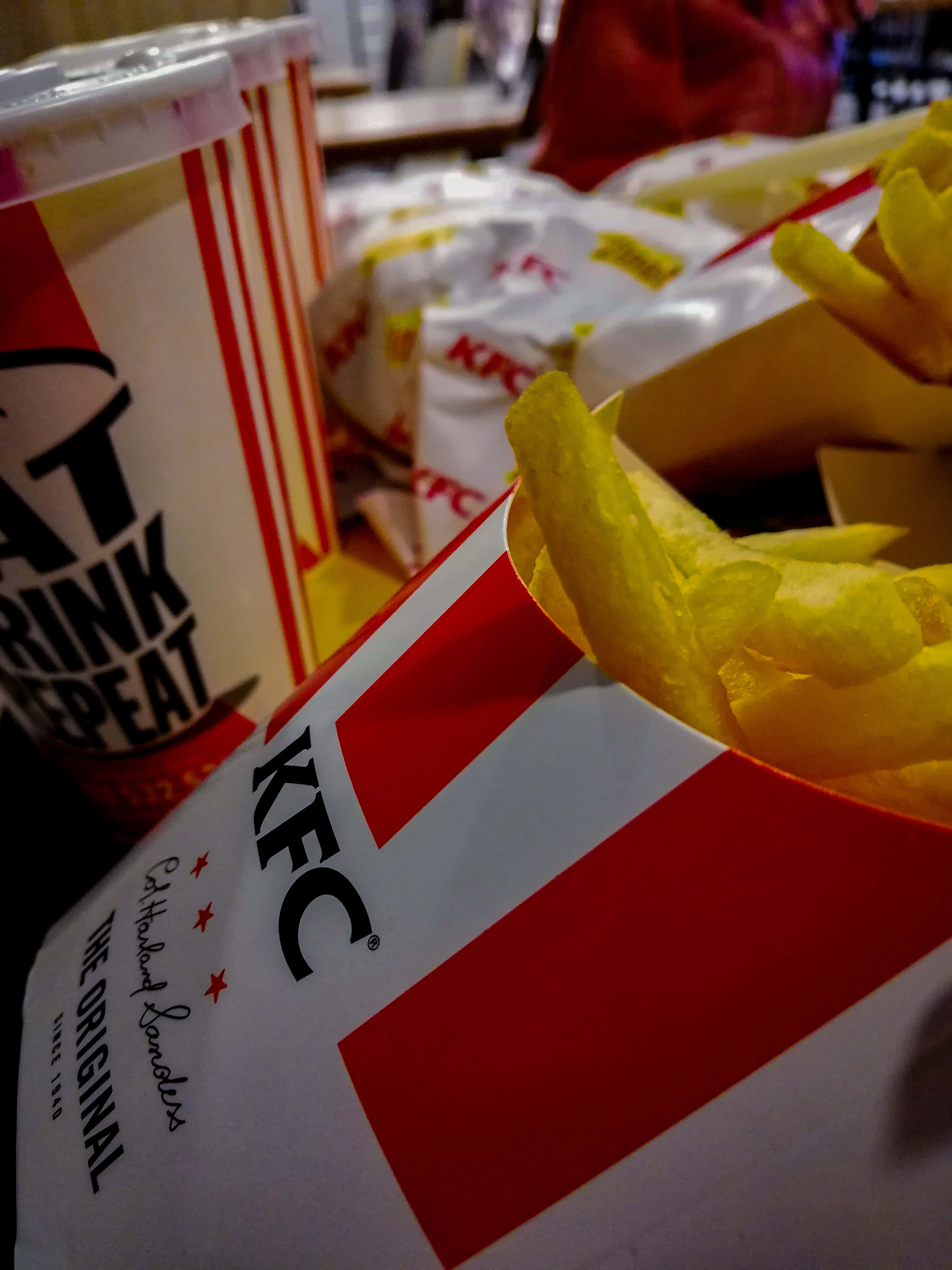 Kfc 桌布 壁紙 — 金黃酥脆的薯條從紅白相間的KFC盒子中溢出，旁邊放著一個品牌飲料杯，營造出休閒用餐的氛圍。