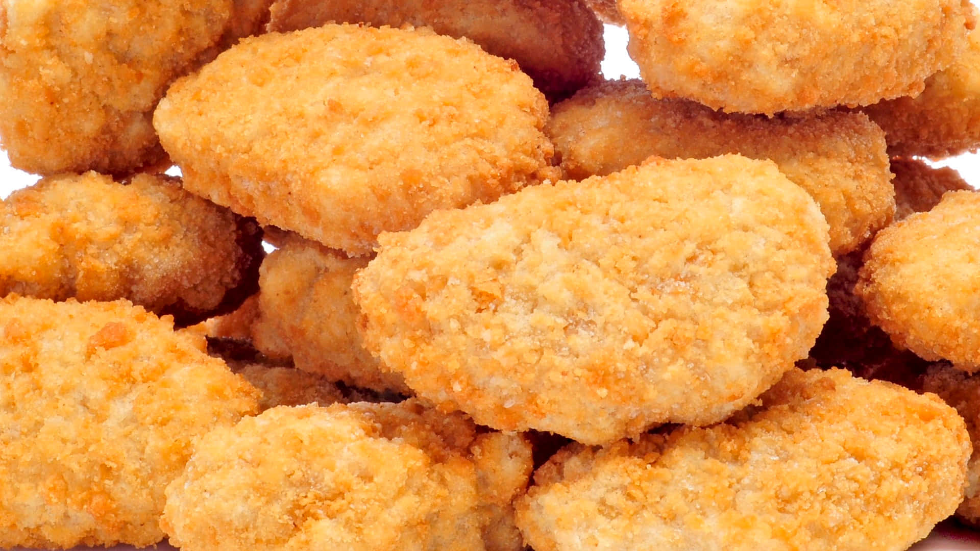 Chicken Nuggets 桌布 壁紙 — 金黃酥脆雞塊堆疊在一起的特寫，背景為白色。