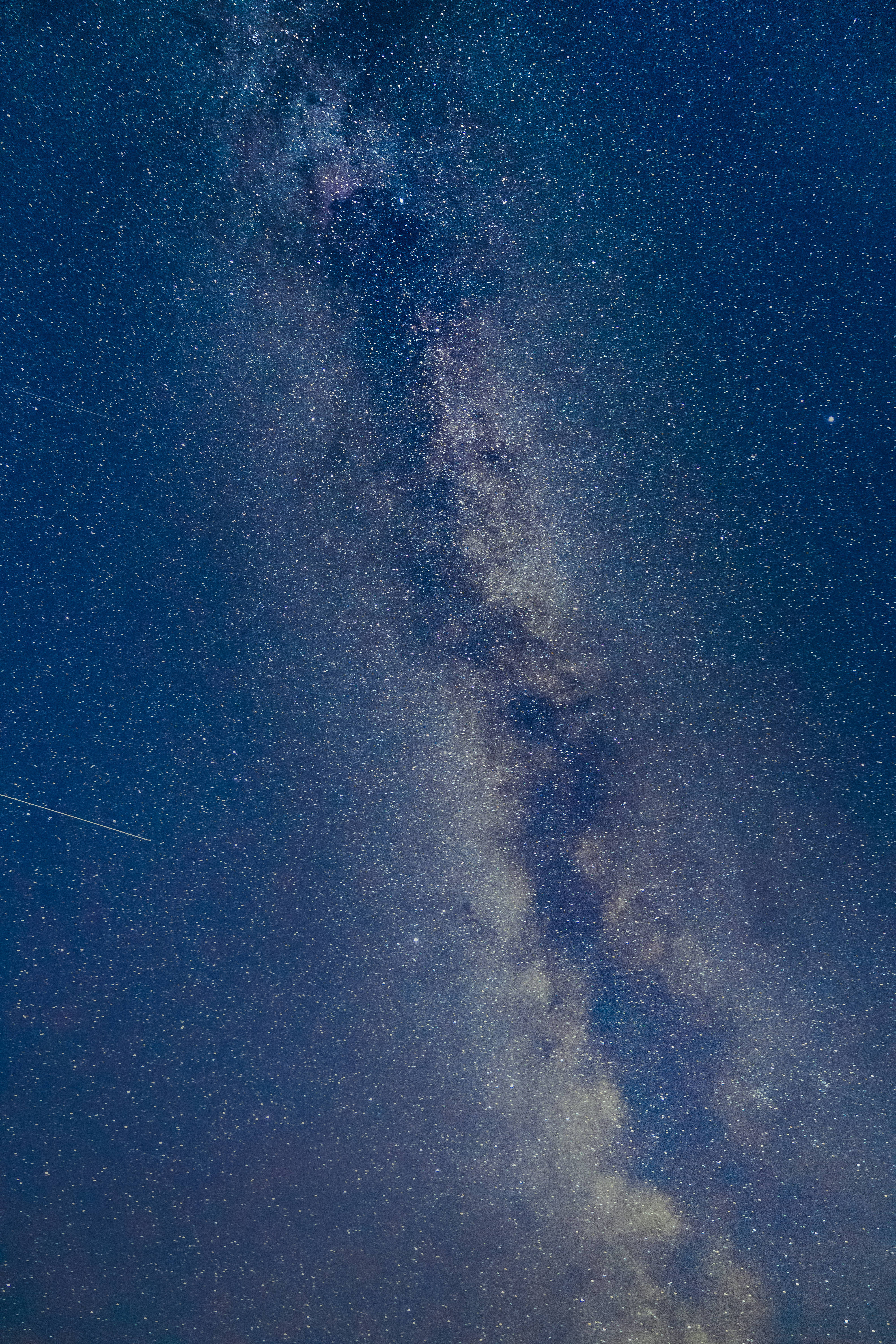 iOS 11 桌布 壁紙 — 銀河系在深藍色夜空中對角延伸，點綴著無數星星和微弱的宇宙塵埃帶，令人嘆為觀止。