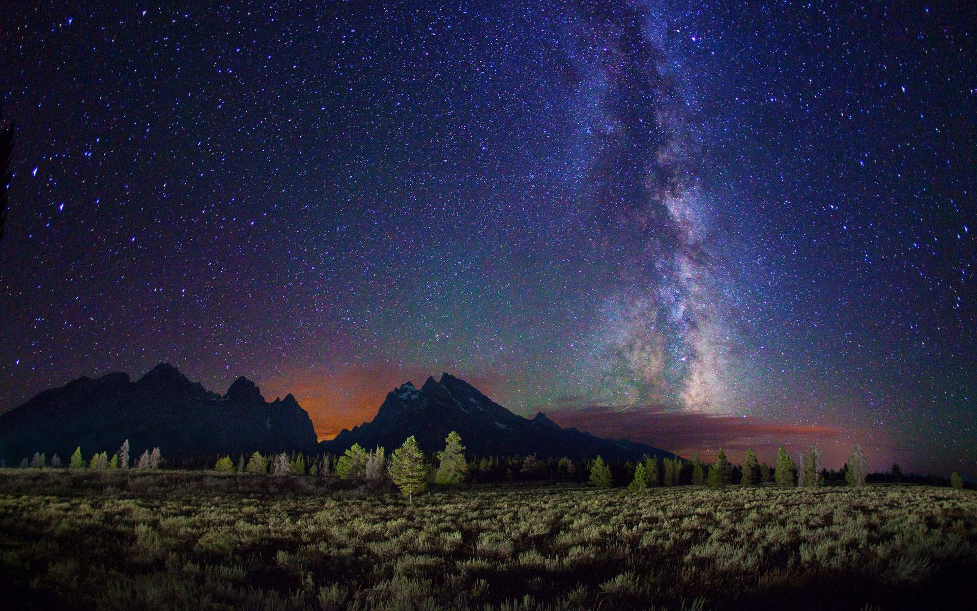 夜空 桌布 壁紙 — 銀河系在繁星點點的夜空下，在崎嶇的山峰上燦爛地拱起。