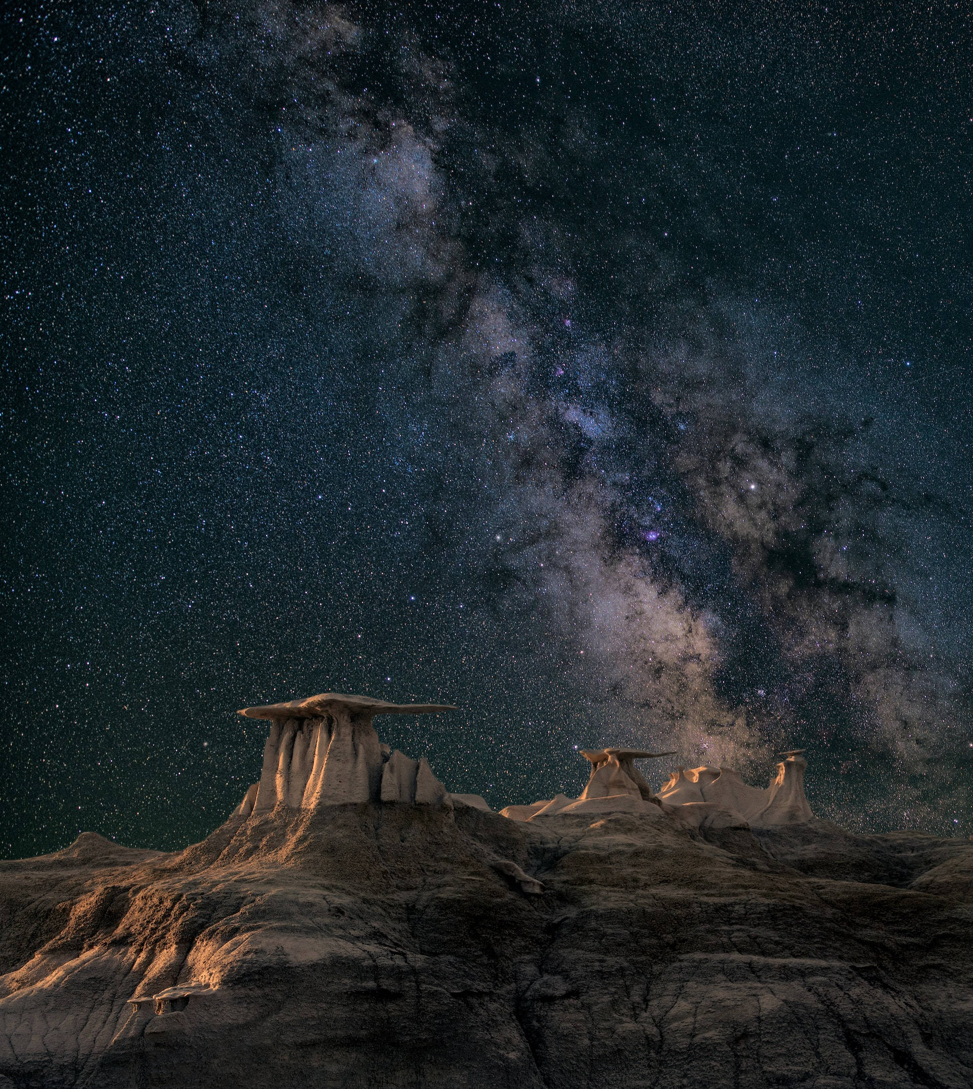 夜空 桌布 壁紙 — 銀河系在繁星點點的夜空下，在崎嶇的沙漠岩石層上燦爛地彎曲。