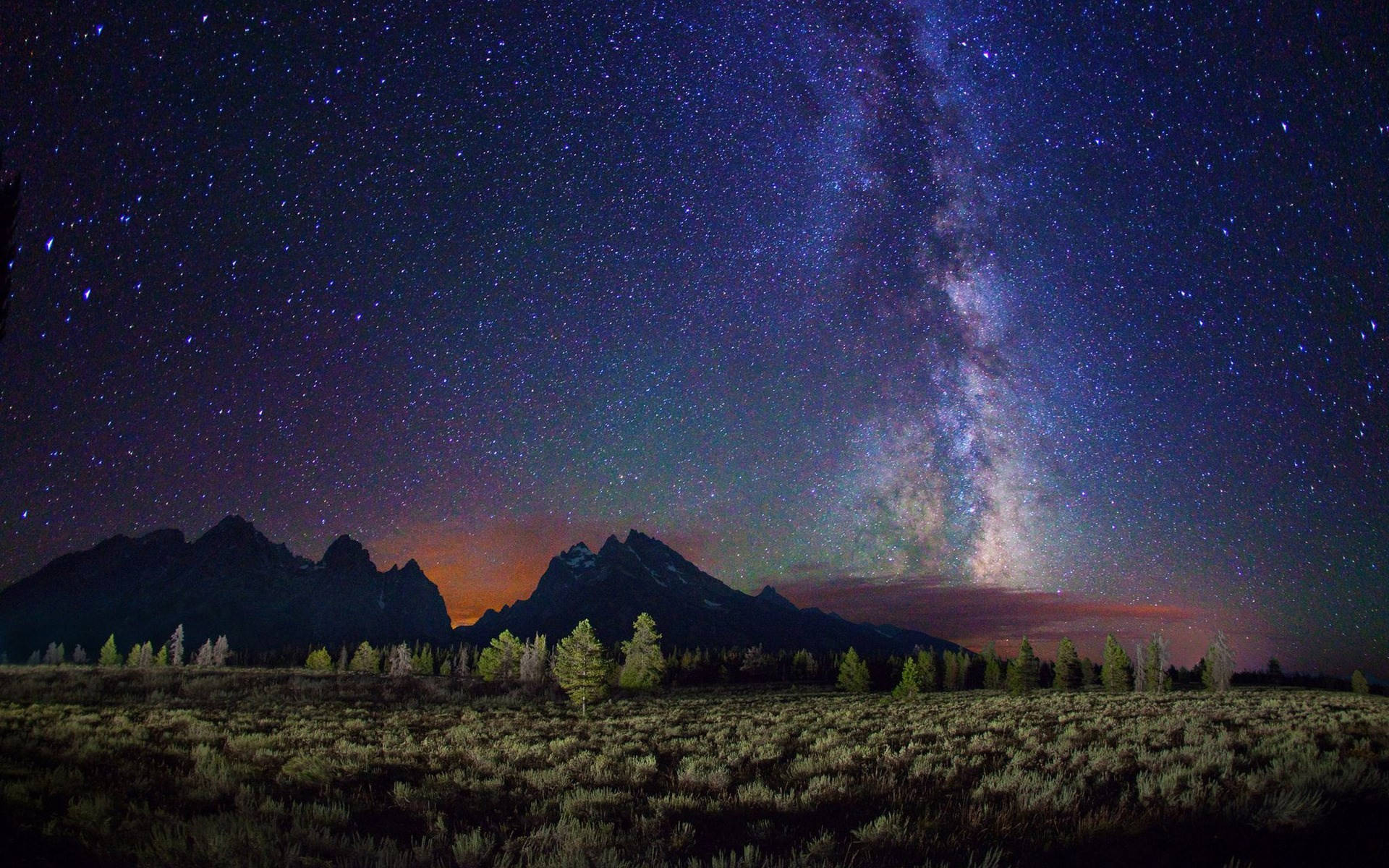 Sky HD 桌布 壁紙 — 銀河系在繁星點點的夜空下，在崎嶇的山峰上燦爛地拱起。