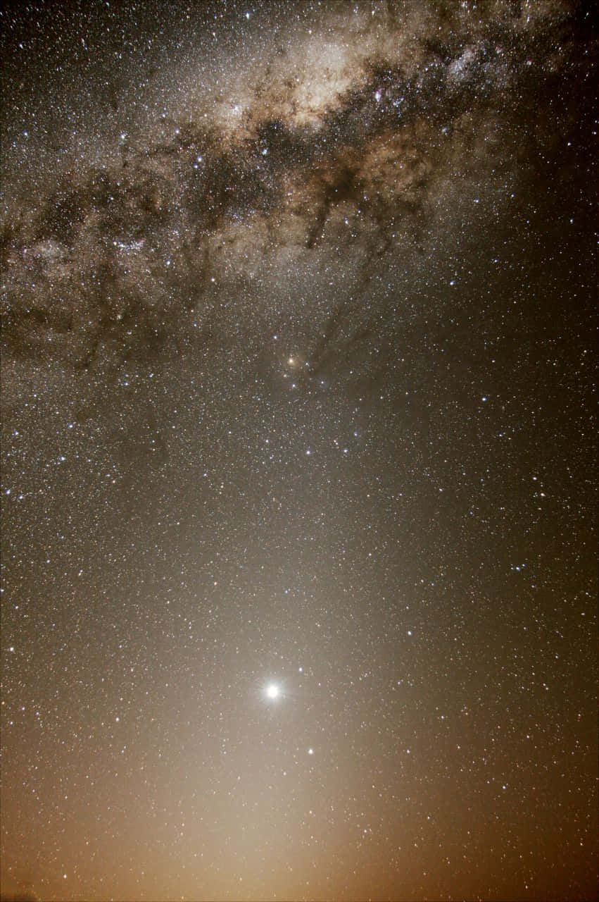 Galactic Center 桌布 壁紙 — 銀河系橫跨滿天繁星的夜空，下方有明亮天體閃耀的壯麗景色。