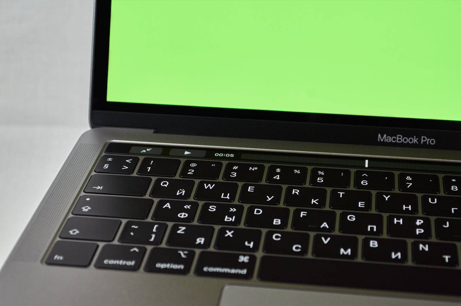 銀色 MacBook Pro，配備西里爾字母鍵盤及顯示計時器的綠色螢幕。