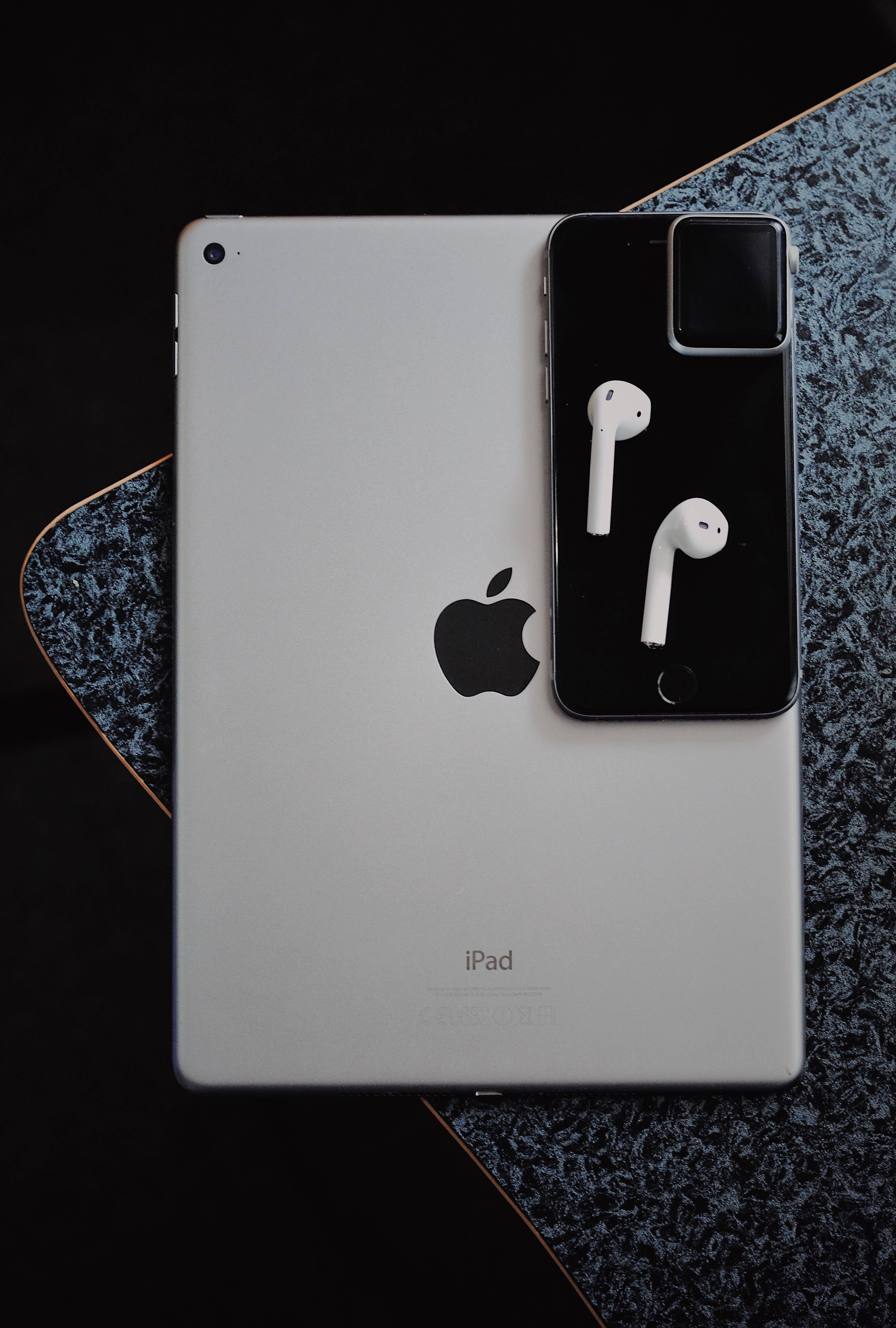MacBook 動態圖片 桌布 壁紙 — 銀色iPad和黑色智慧型手機搭配白色耳塞，以極簡平鋪方式放置在深色斑點表面上。
