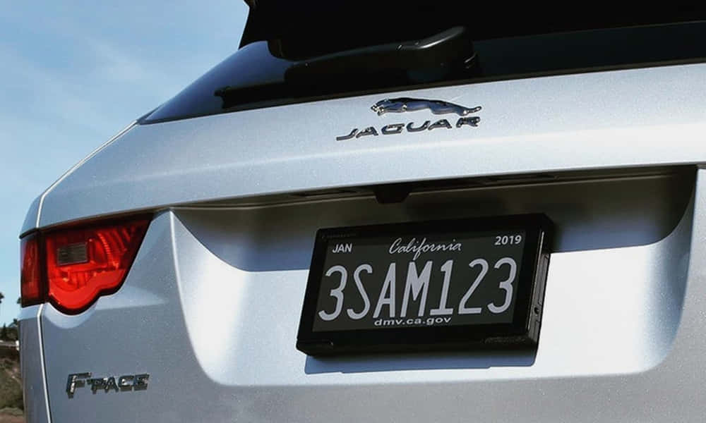 Car License Plate 桌布 壁紙 — 銀色Jaguar F-PACE SUV車尾特寫，在明亮日光下展示其標誌尾燈和加州車牌。