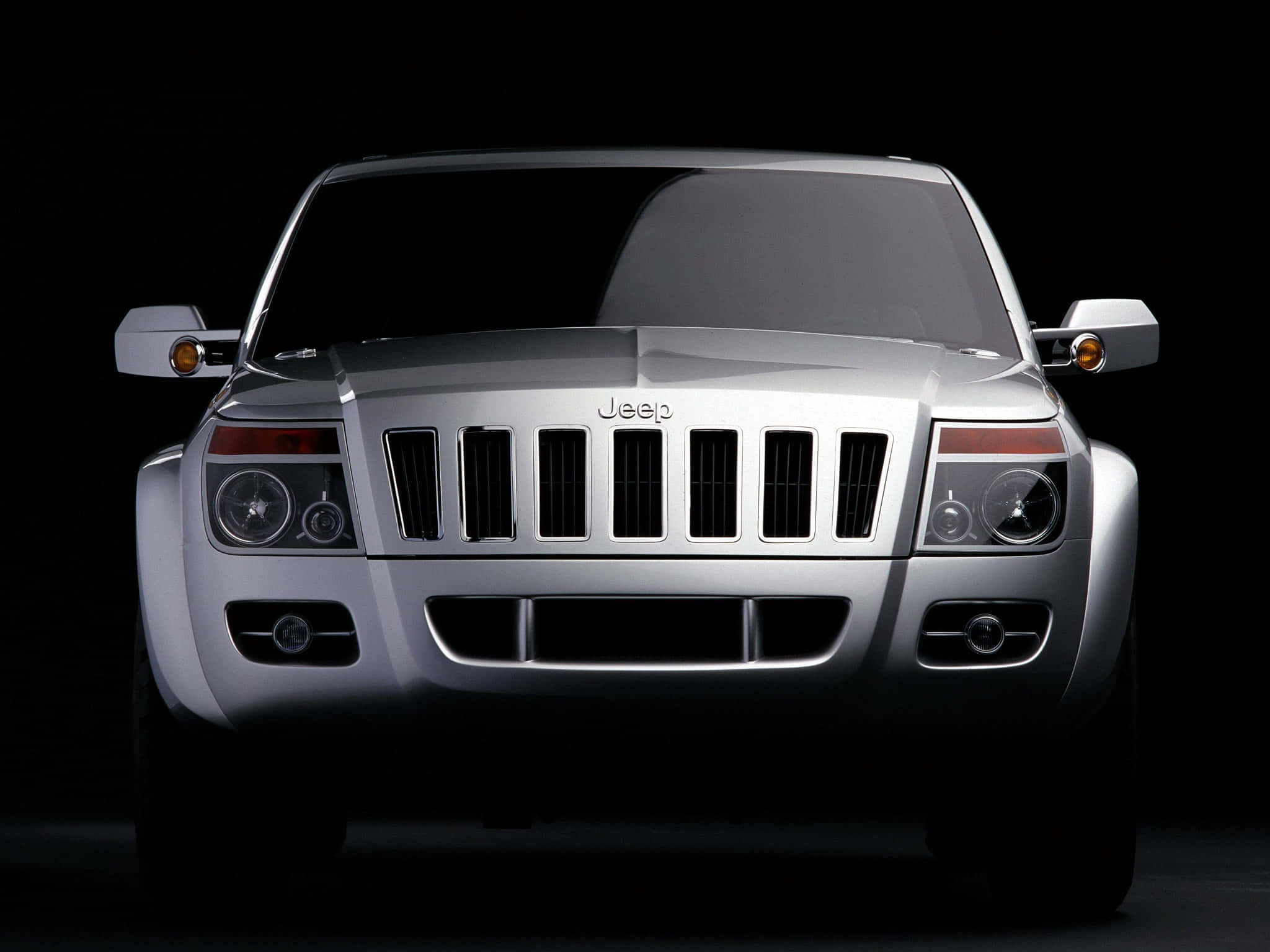 Jeep Commander 桌布 壁紙 — 銀色Jeep SUV的前視圖，在黑色背景上照亮，突出其大膽的格柵和頭燈。