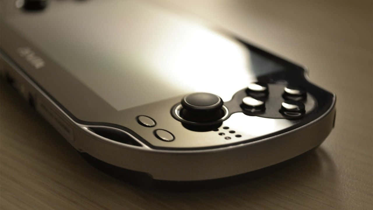 Ps Vita 桌布 壁紙 — 銀色PlayStation Portable特寫，放置在木質表面上，帶有柔和溫暖的燈光。