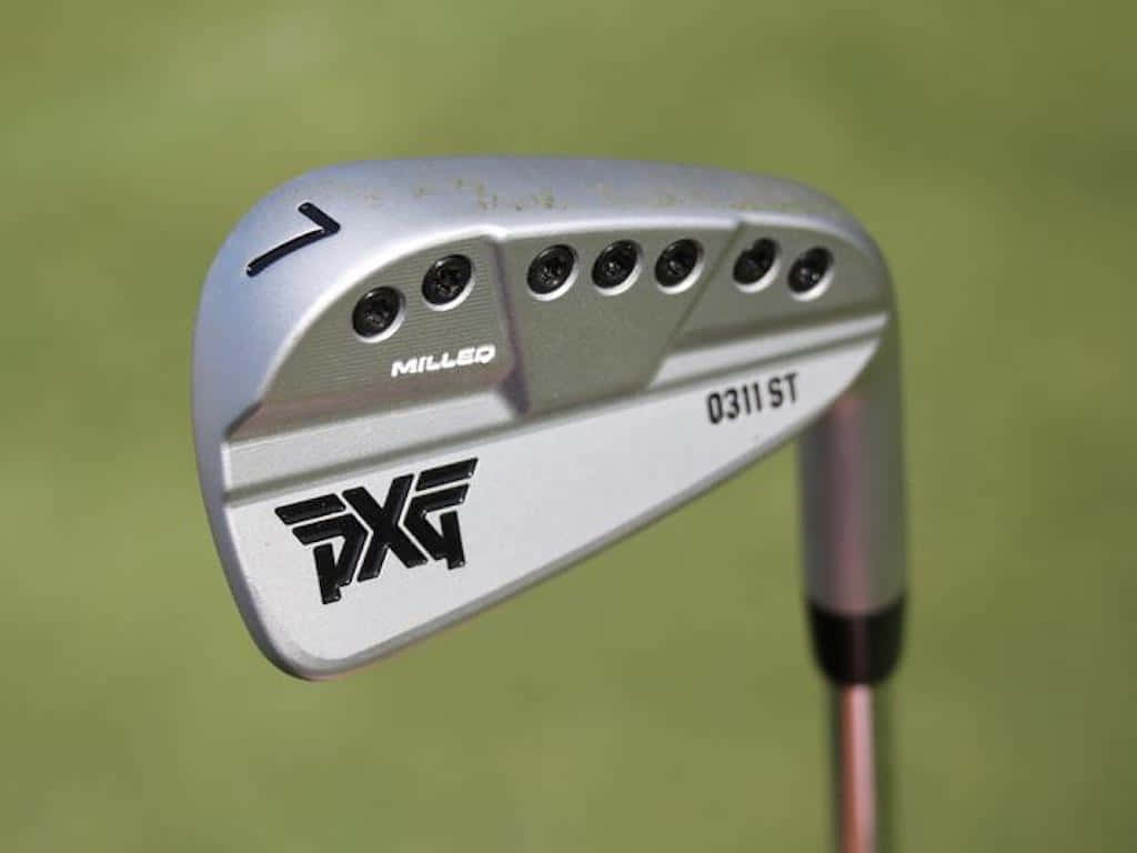 Golf Club 桌布 壁紙 — 銀色PXG高爾夫鐵桿的特寫，帶有銑削桿面和數字七，背景為模糊的綠色。