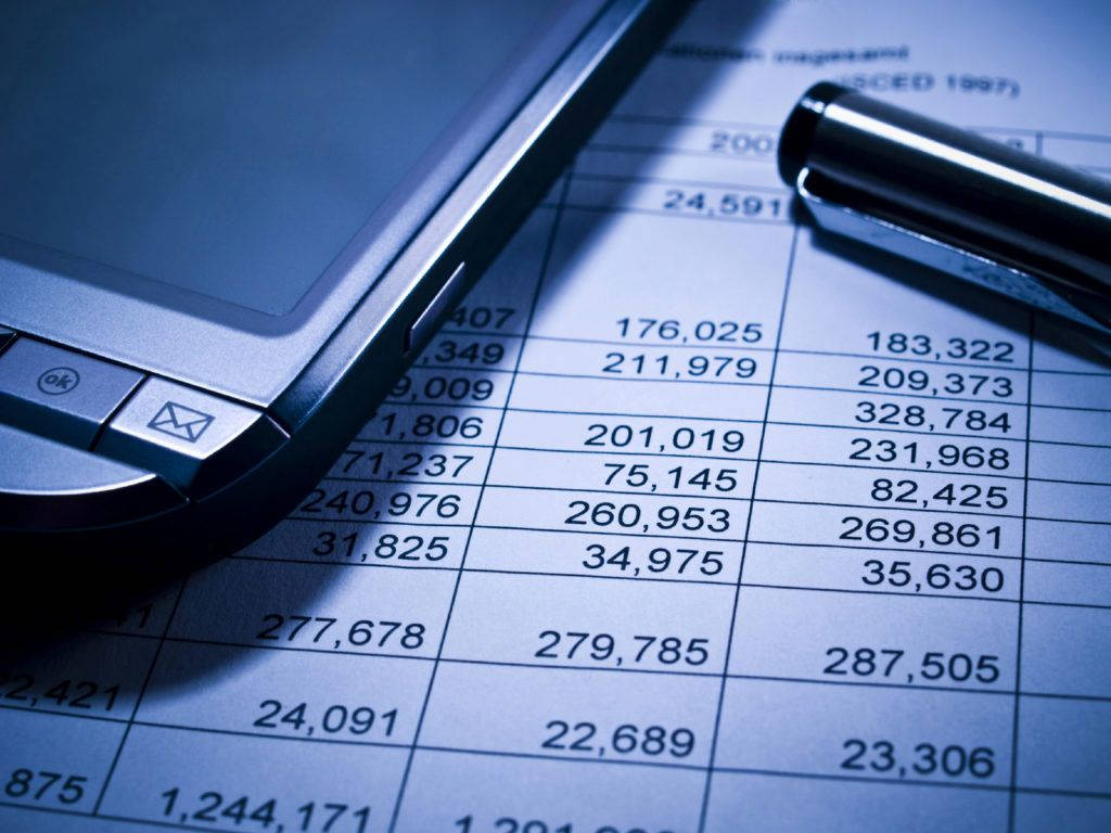會計 桌布 壁紙 — 銀色摺疊手機和筆在冰冷藍光下放在充滿財務數字的試算表上的特寫。