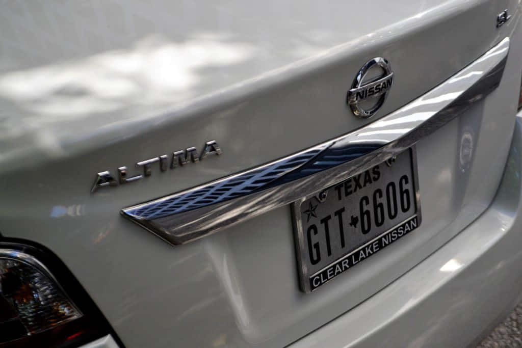 License Plate 桌布 壁紙 — 銀色日產Altima後車廂特寫，帶有德州車牌和經銷商品牌標識。