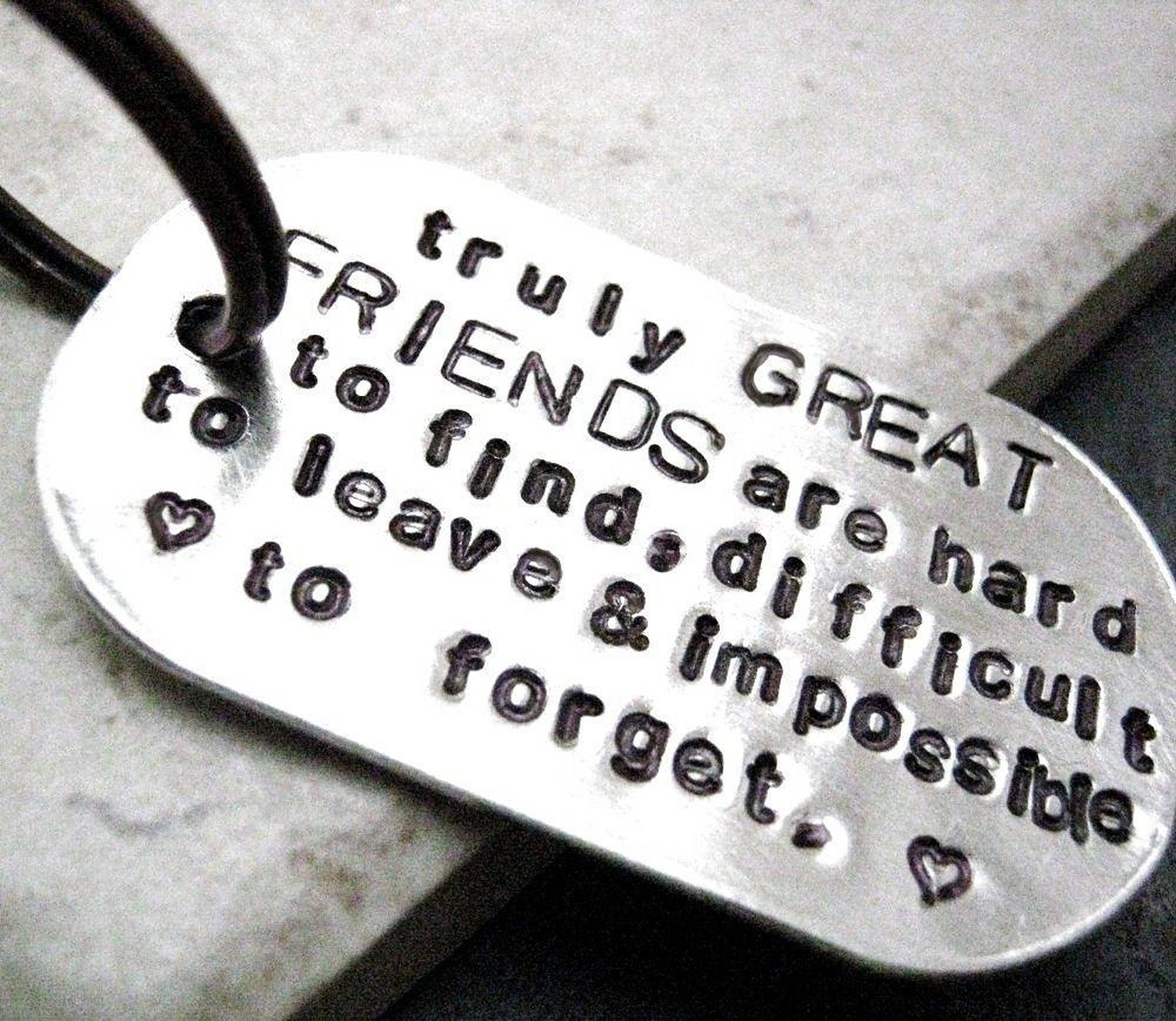 Friendship Quotes 桌布 壁紙 — 銀色狗牌特寫，刻有關於真正朋友和兩個心形符號的衷心訊息。
