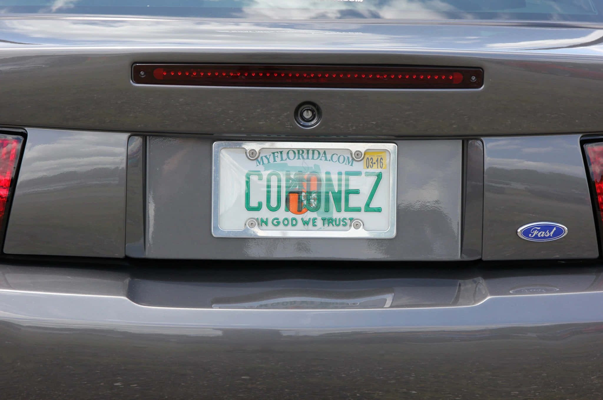 Car License Plate 桌布 壁紙 — 銀色福特汽車後部的特寫，顯示佛羅里達州車牌上有「CORONEZ」和「IN GOD WE TRUST」字樣。