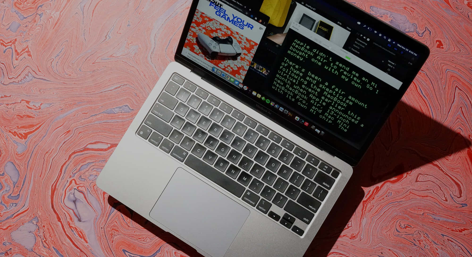 MacBook 動態圖片 桌布 壁紙 — 銀色筆記型電腦打開在旋轉的粉紅色和紫色大理石表面上，顯示遊戲內容和文字。