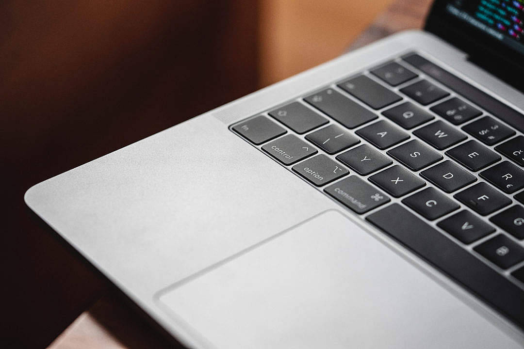 Macbook Air 2020 桌布 壁紙 — 銀色筆記型電腦鍵盤的特寫，黑色按鍵，發光螢幕顯示彩色程式碼。