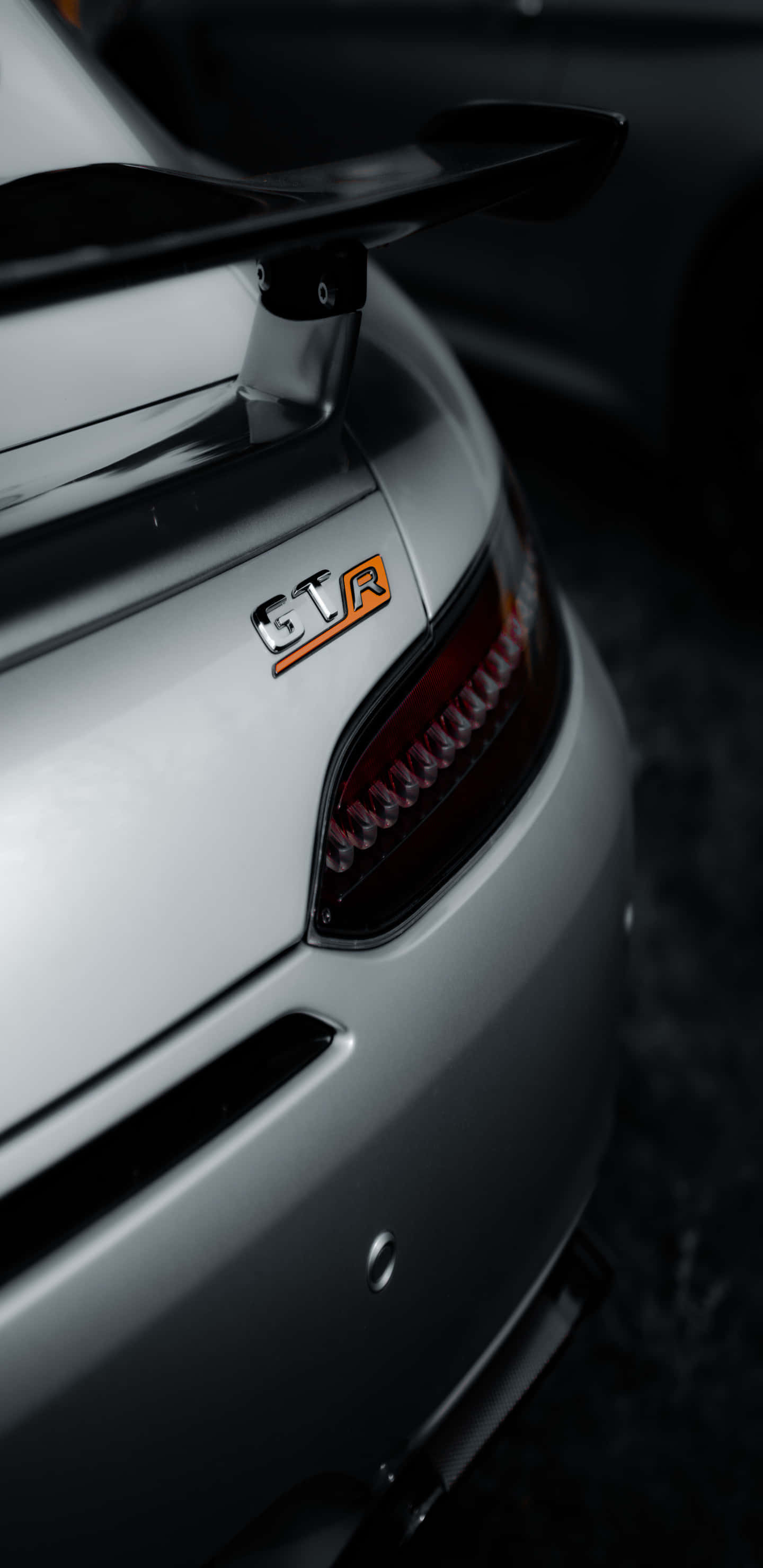 cars 桌布 壁紙 — 銀色跑車尾部特寫，帶有橙色STR徽章和時尚尾燈，背景為深色。