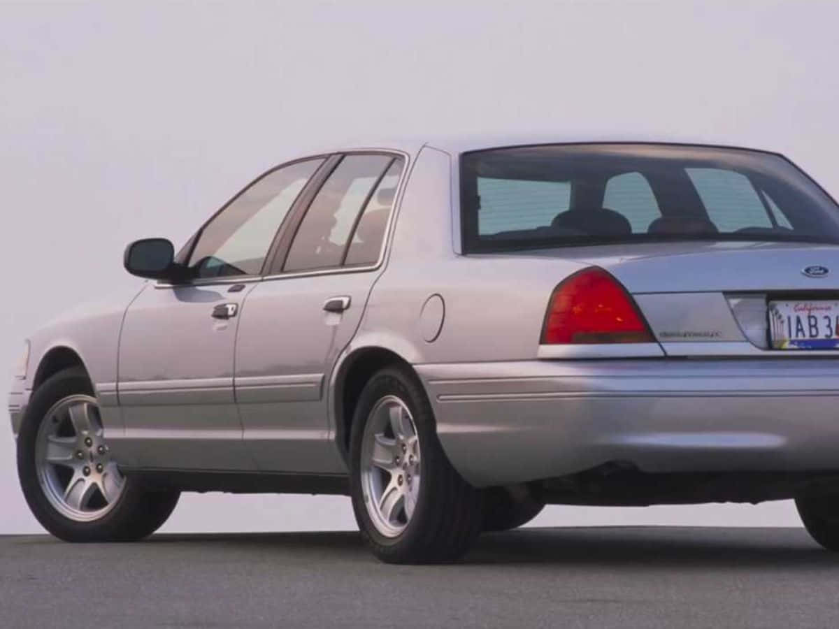 Ford Crown Victoria 桌布 壁紙 — 銀色轎車停在瀝青路上，在明亮的日光下，加州車牌清晰可見。