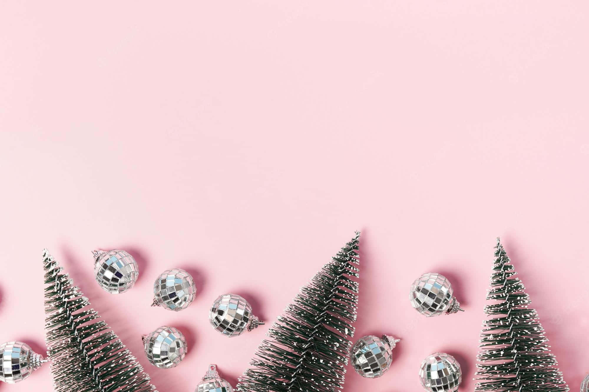 Pink Christmas Tree 桌布 壁紙 — 銀色迪斯可球裝飾品和微型樹木排列在柔和的粉紅色背景上。