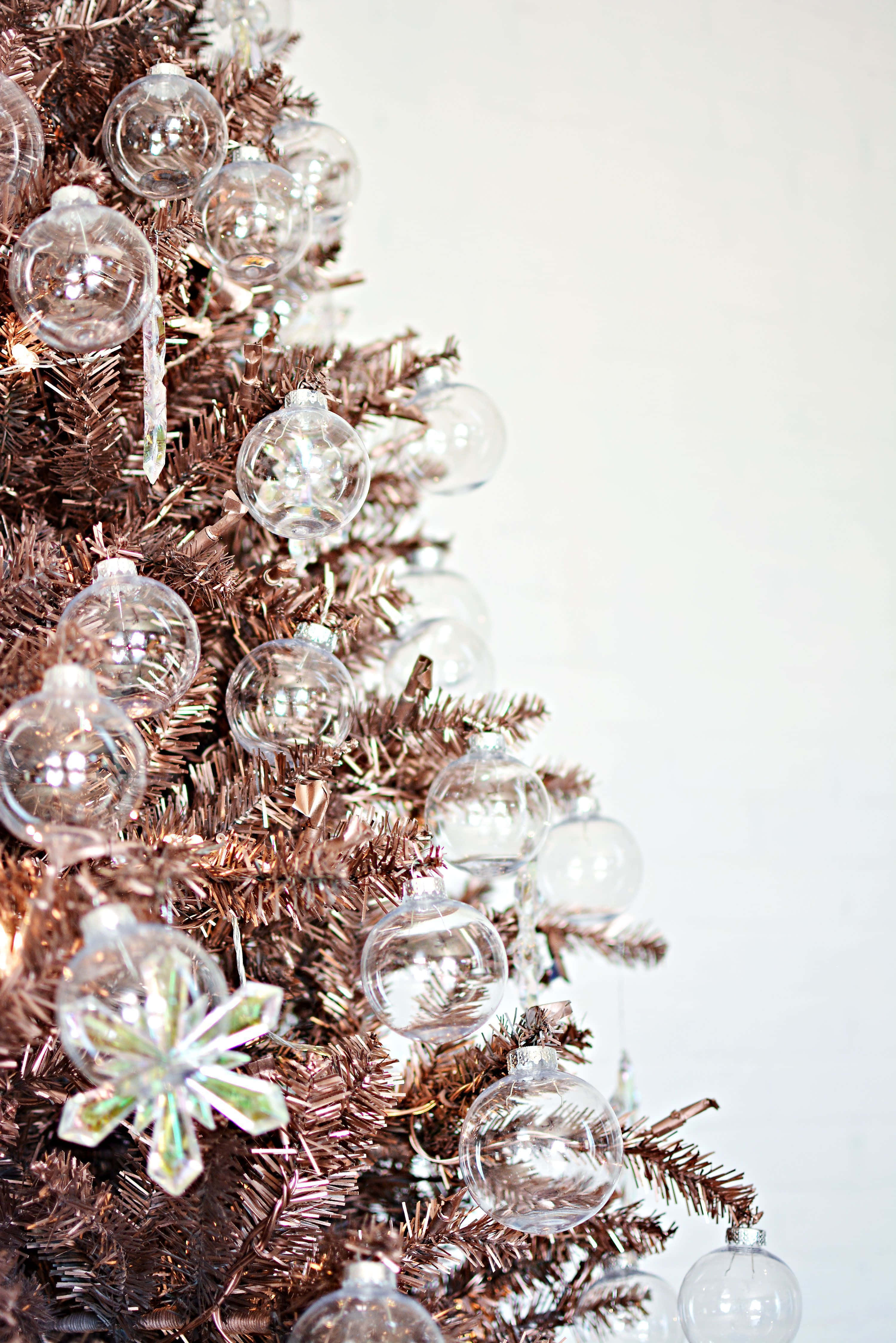 Aesthetic Christmas Tree 桌布 壁紙 — 銅色閃粉聖誕樹的特寫，飾有透明玻璃裝飾和閃爍雪花裝飾。