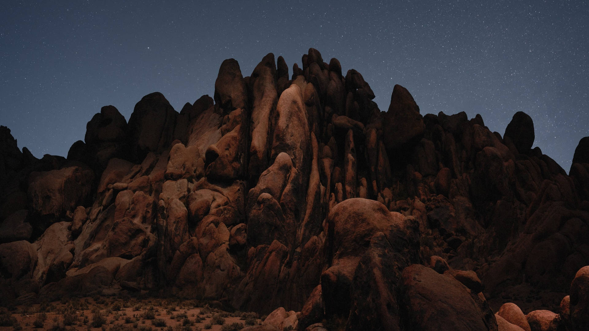 Mojave 桌布 壁紙 — 鋸齒狀岩石輪廓映襯著星空夜空，帶有深藍色和溫暖的大地色調。