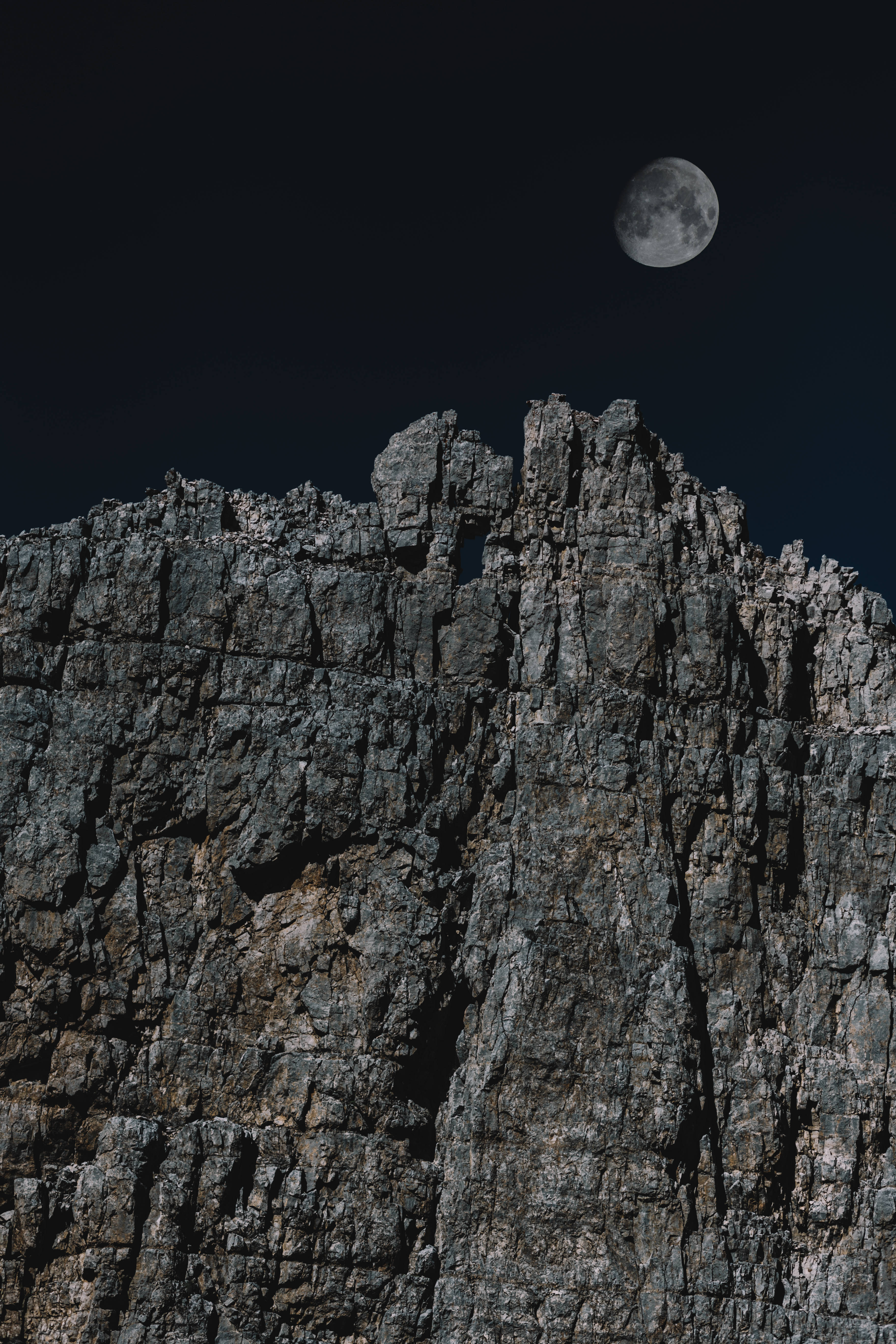 HD Moon 桌布 壁紙 — 鋸齒狀的山峰在黑暗的天空中形成剪影，上方懸掛著一輪明亮的月亮。