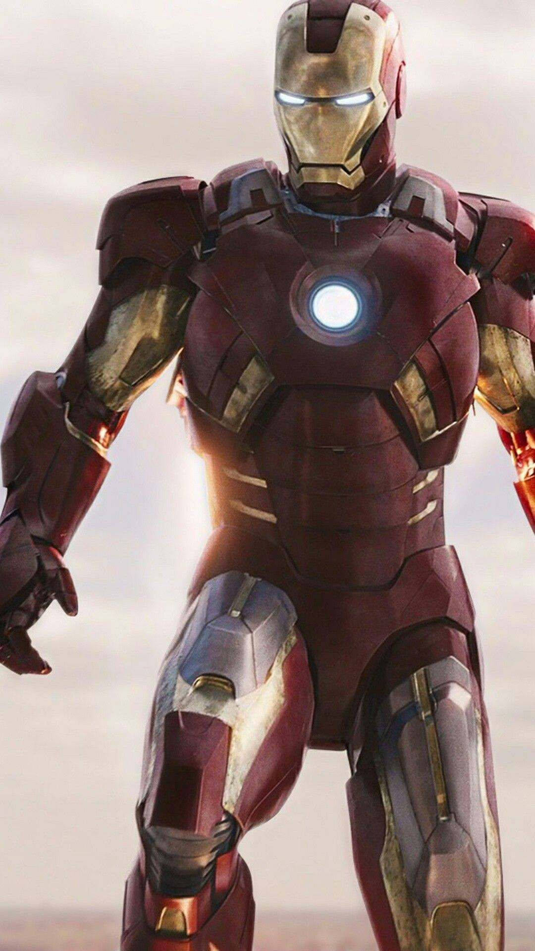 Iron Man Mark 3 桌布 壁紙 — 鋼鐵人以英雄姿態站立，方舟反應爐和雙眼發光，背景是朦朧的天空。