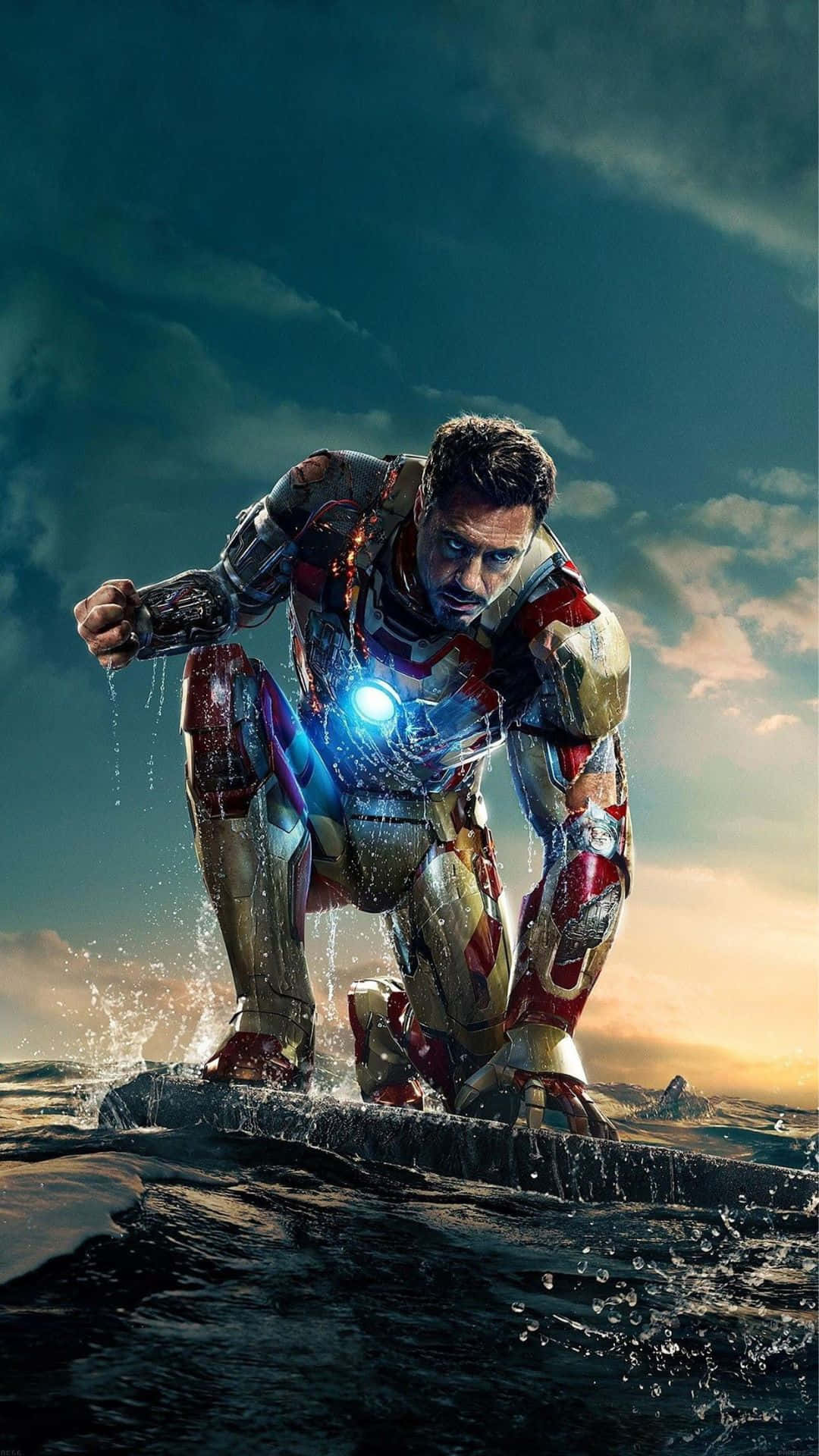 Android Iron Man 桌布 壁紙 — 鋼鐵人在日落時從海洋水中出現，發光的弧形反應堆和周圍飛濺的水滴。