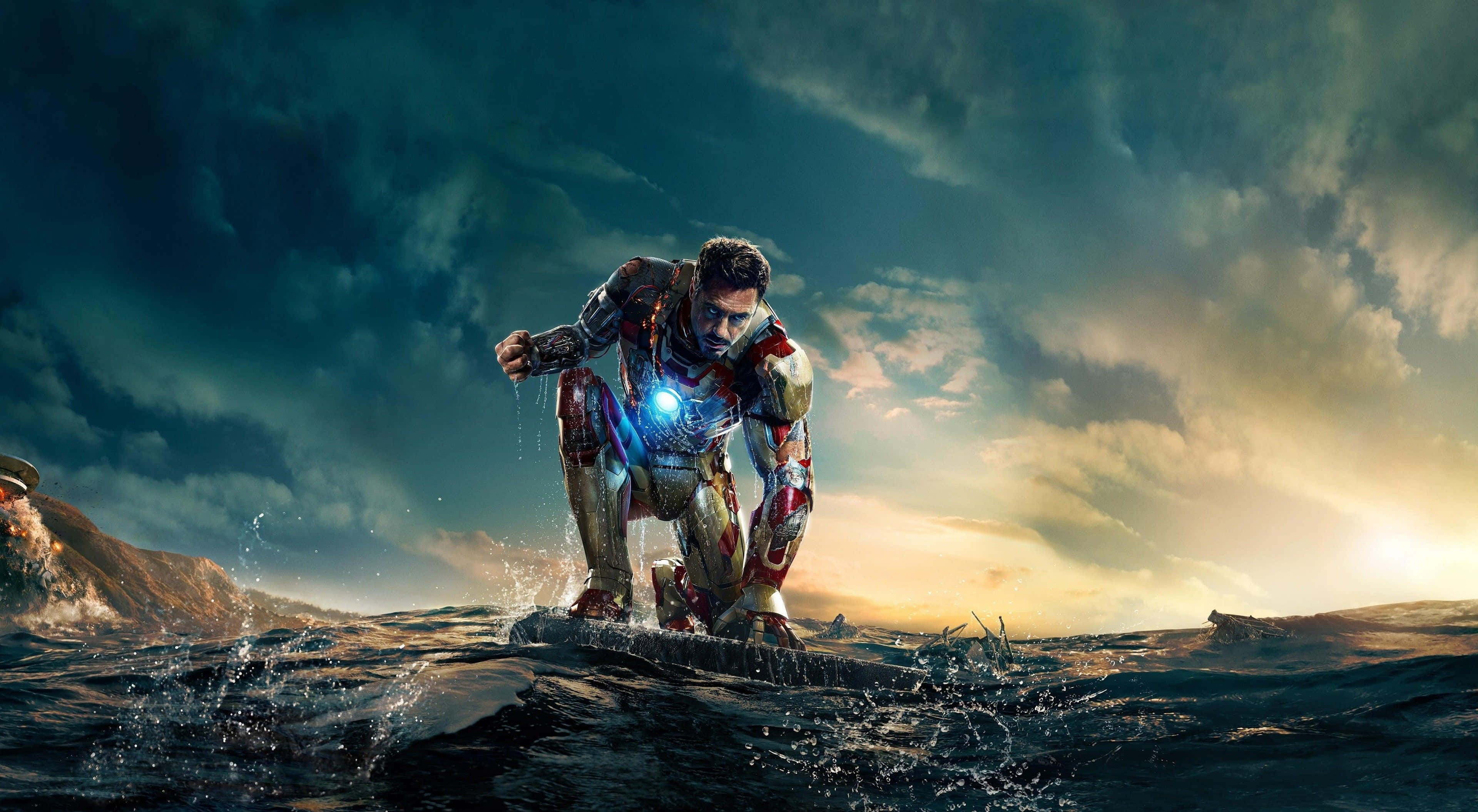 4K Marvel 壁紙 桌布 壁紙 — 鋼鐵人在波濤洶湧的海水中蹲伏，背景是戲劇性的日落天空，胸口反應爐閃閃發光。