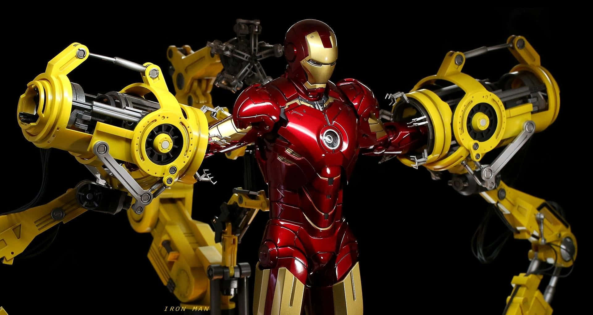 Iron Man Suit 桌布 壁紙 — 鋼鐵人穿著紅色和金色裝甲，居中站立，兩側伸出巨大的黃色機械臂，背景為黑色。