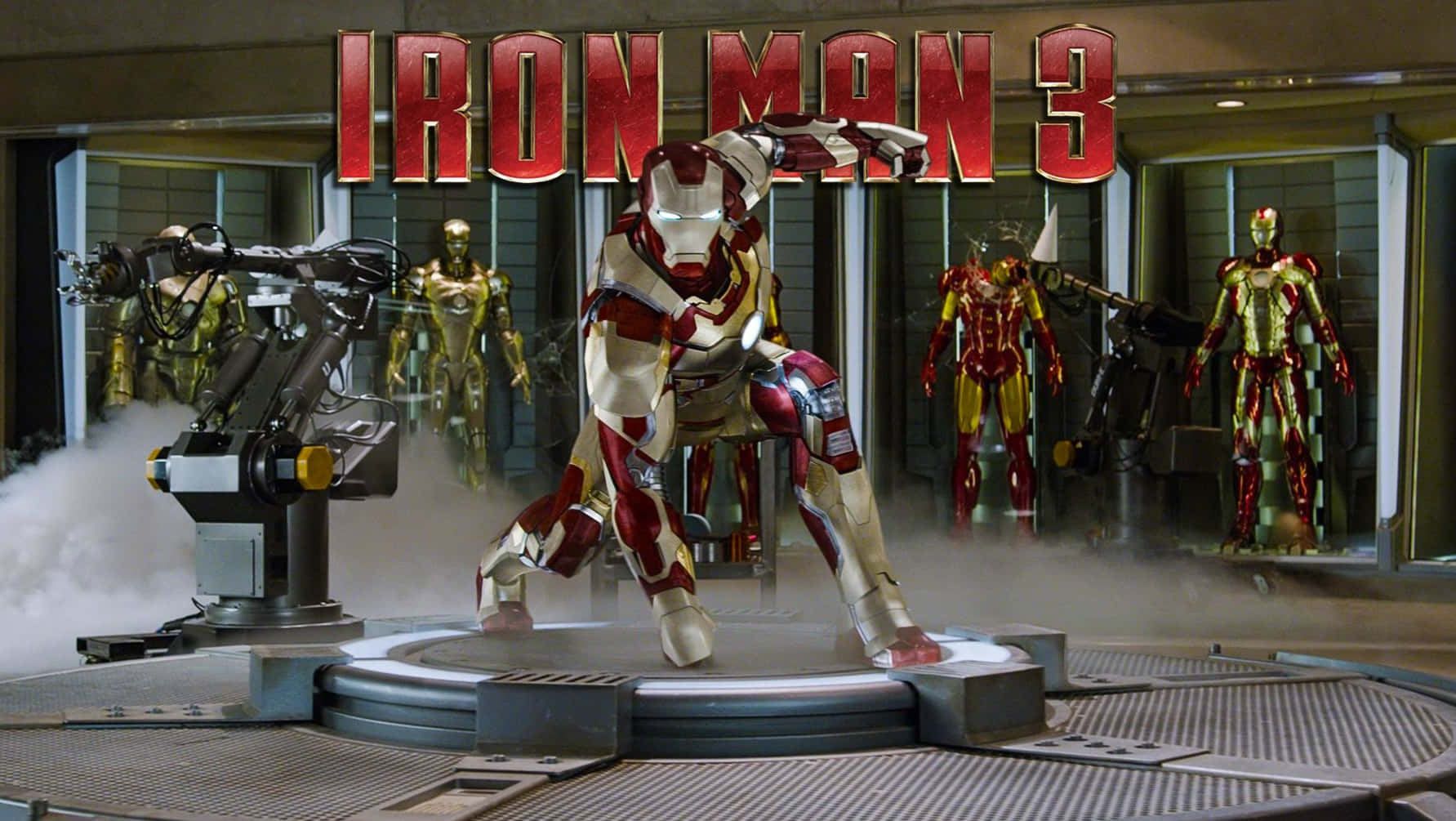 iron man 3 桌布 壁紙 — 鋼鐵人穿著紅金裝甲，站在高科技實驗室的圓形平台上，周圍有其他戰衣，上方有電影標題。