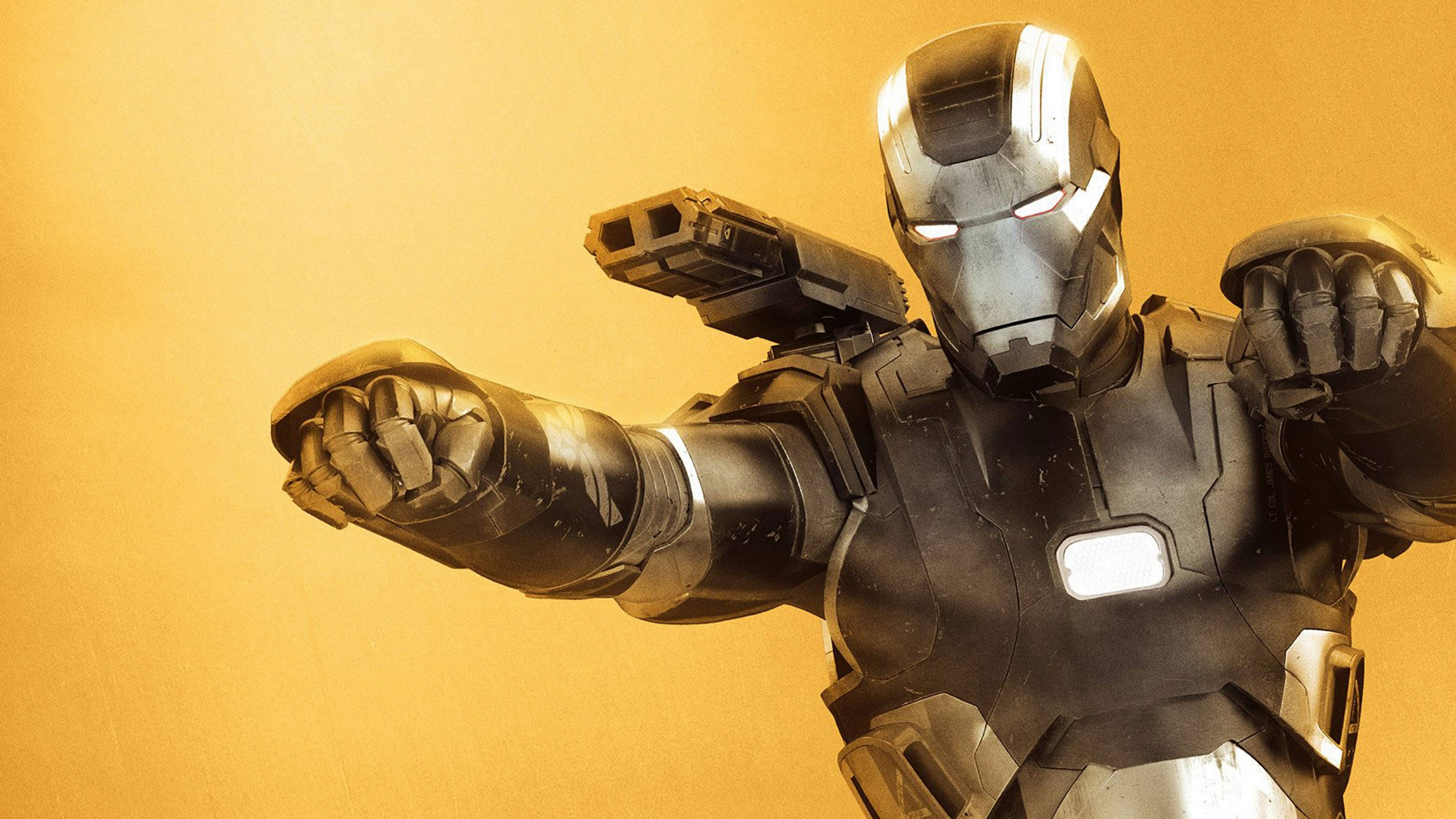 avengers infinity war 4K 桌布 壁紙 — 鋼鐵人穿著裝甲，眼睛發光，手持斥力武器，站在溫暖的金色背景前。