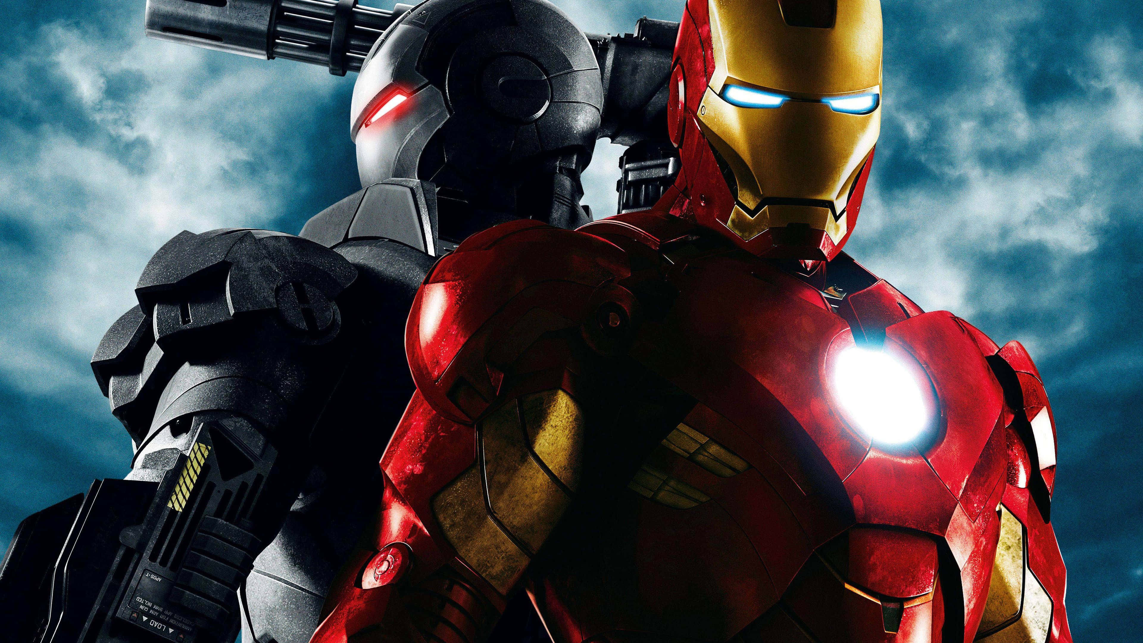Iron Man Movies 桌布 壁紙 — 鋼鐵人與戰爭機器身穿細節豐富的戰甲，在暴風雨的天空下並肩而立，眼睛和胸口燈光閃爍。