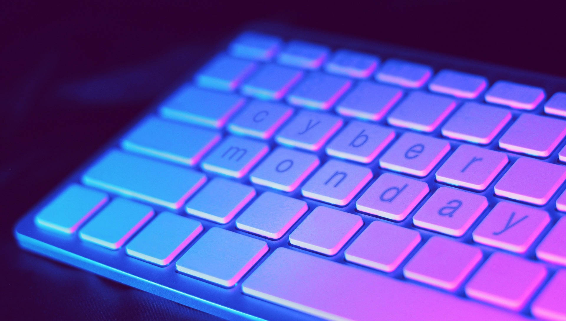 美學 桌布 壁紙 — 鍵盤特寫，發出鮮豔的藍色和紫色背光，拼出「cyber monday」。