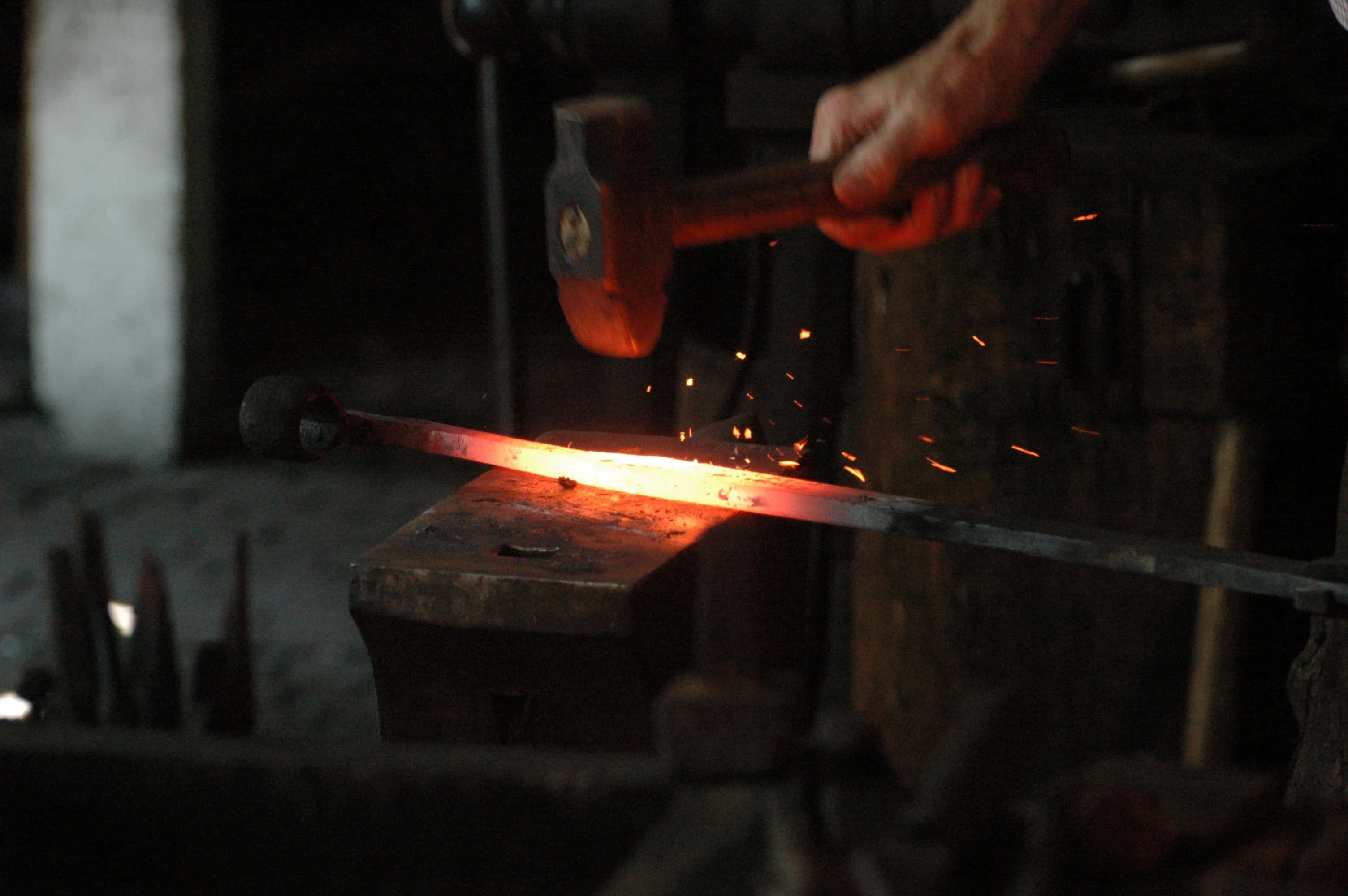 Blacksmith 桌布 壁紙 — 鐵匠的錘子擊打鐵砧上熾熱的金屬棒，火花在昏暗的工場中飛濺。