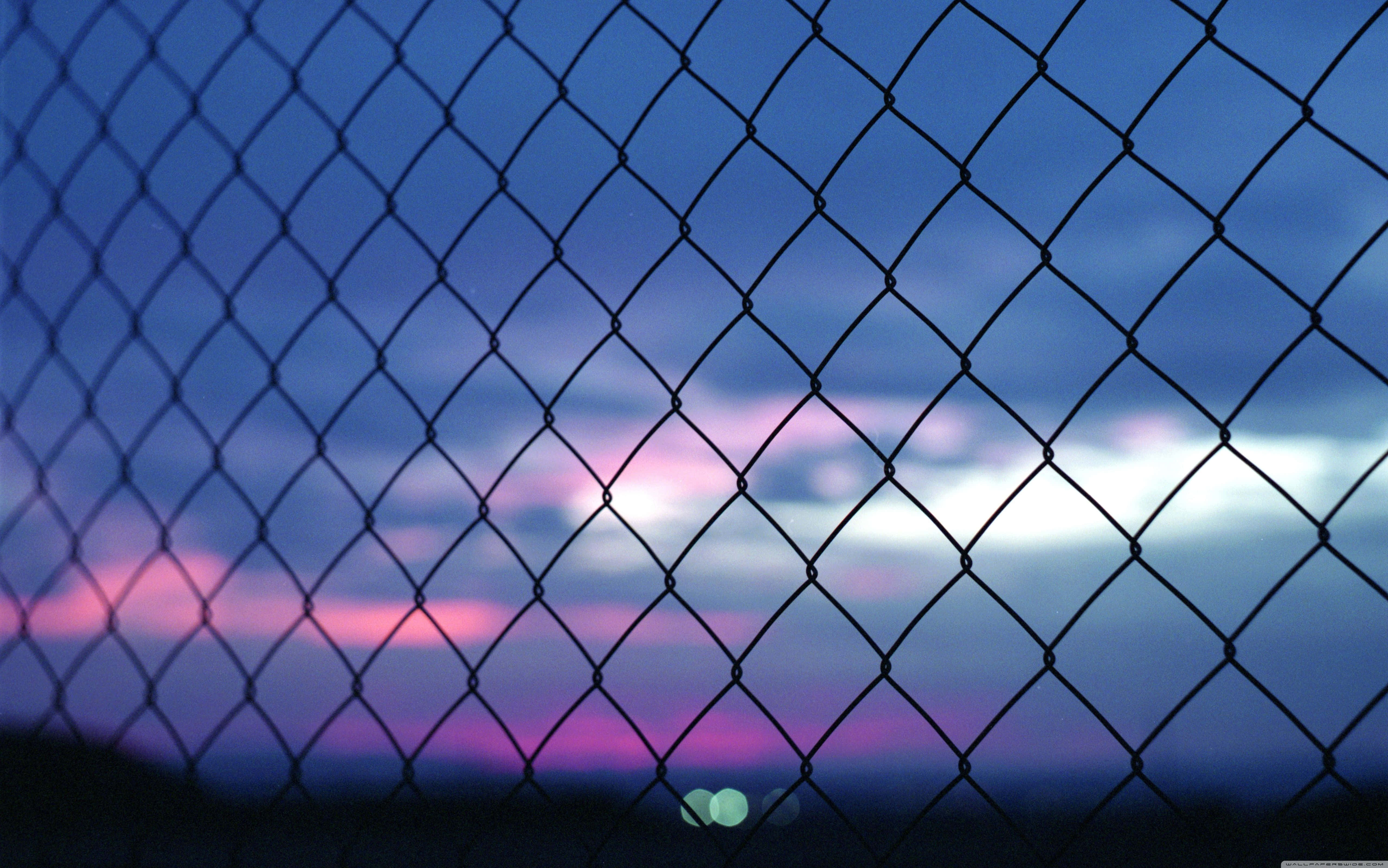 Grunge Aesthetic Mac 桌布 壁紙 — 鐵絲網圍欄框住一片暮色天空，塗上柔和的紫色、粉紅色和藍色。