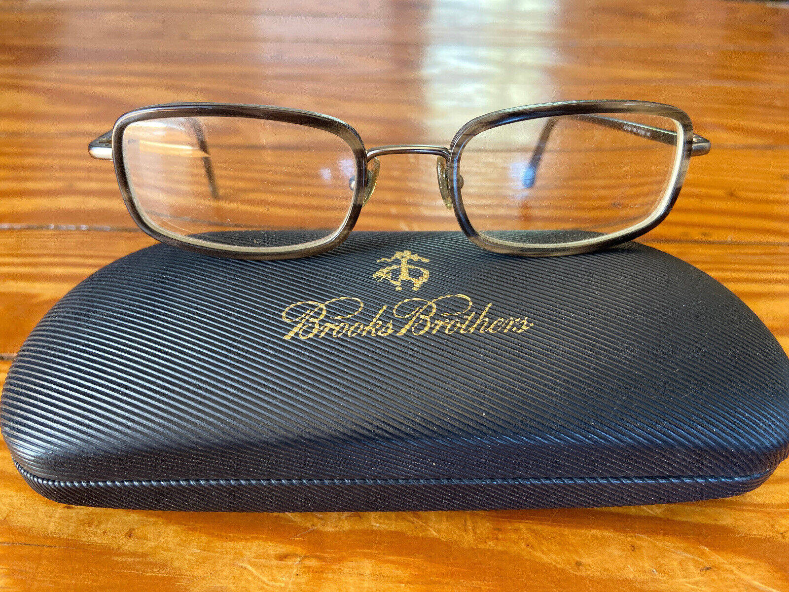 glasses 桌布 壁紙 — 長方形金屬框眼鏡放在溫暖木質表面上的紋理黑色Brooks Brothers眼鏡盒上。