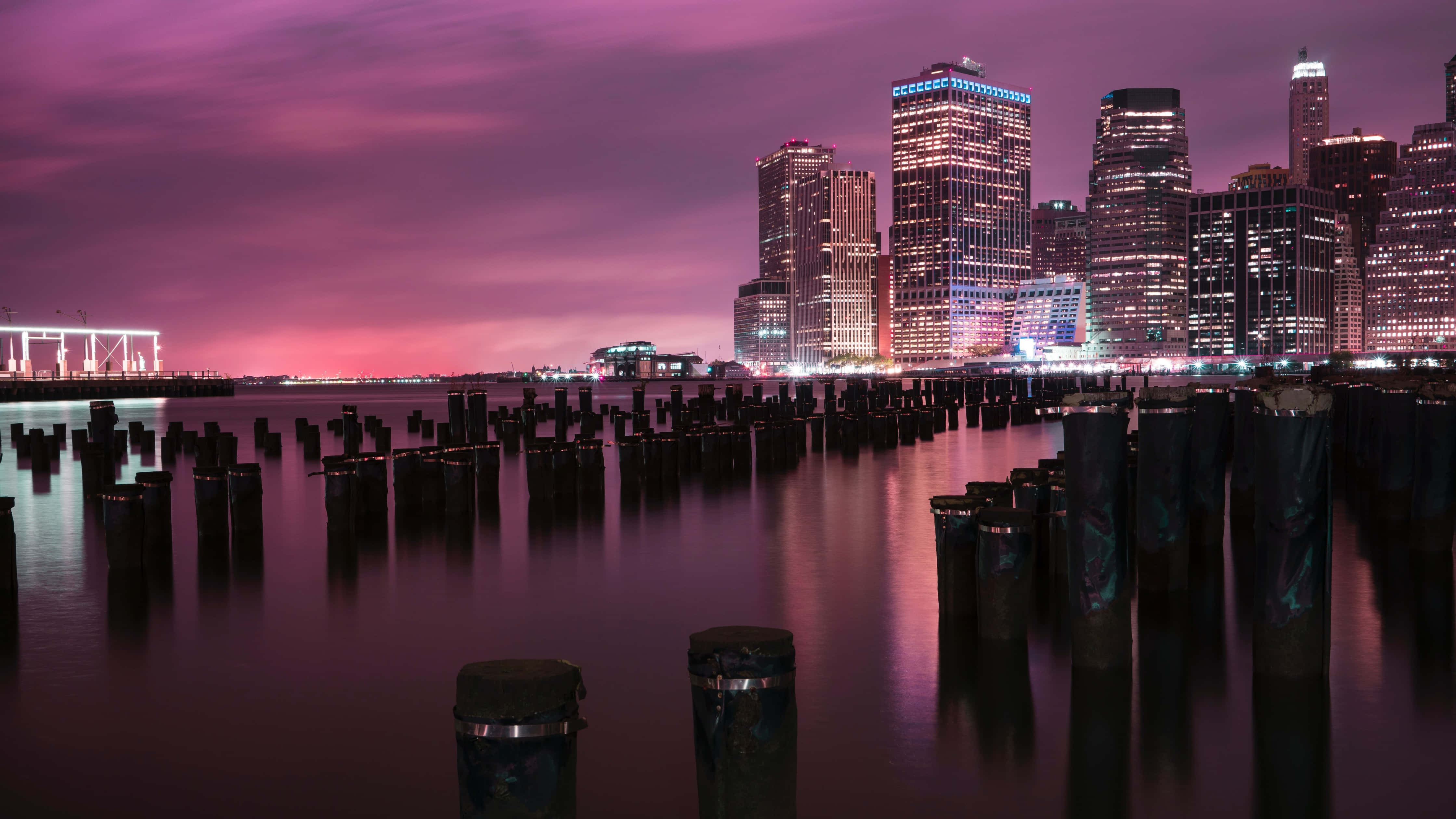 New York City Landscape 桌布 壁紙 — 長時間曝光捕捉到發光的城市摩天大樓在平靜的水面上反射，伴隨著紫色天空的黃昏。