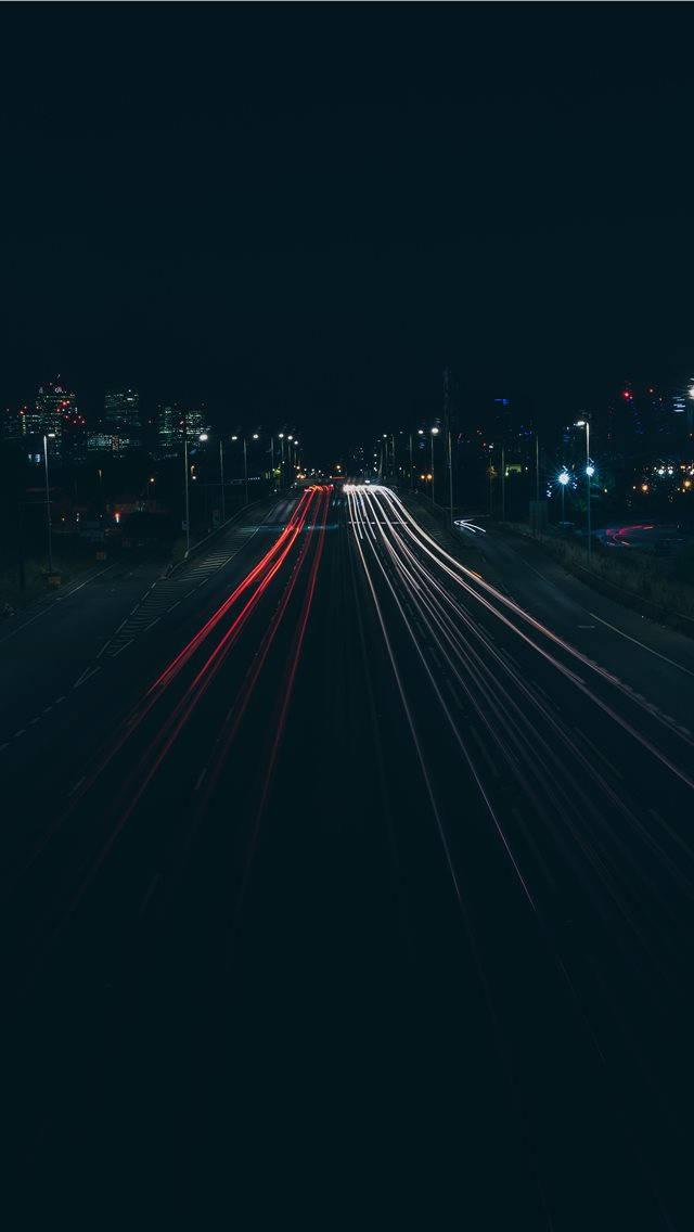 Road 桌布 壁紙 — 長時間曝光捕捉到紅色和白色汽車燈光在夜間黑暗的城市高速公路上飛馳而過的光軌。