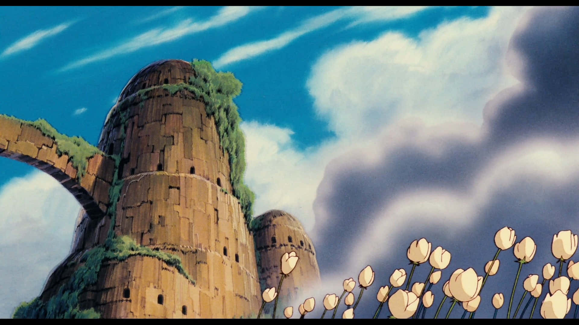 Laputa Castle In The Sky 桌布 壁紙 — 長滿苔蘚的古老石塔在藍天白雲和前景白色花朵的映襯下聳立。