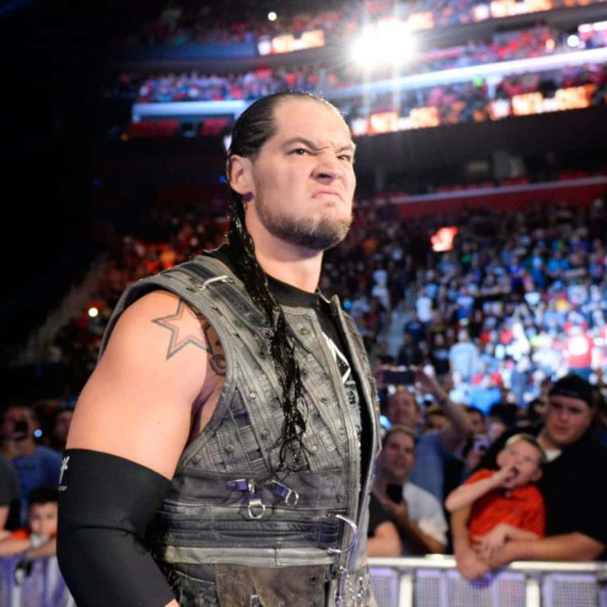 WWE 桌布 壁紙 — 長辮子、星星刺青的摔角手在燈光明亮的競技場中凝視著人群。