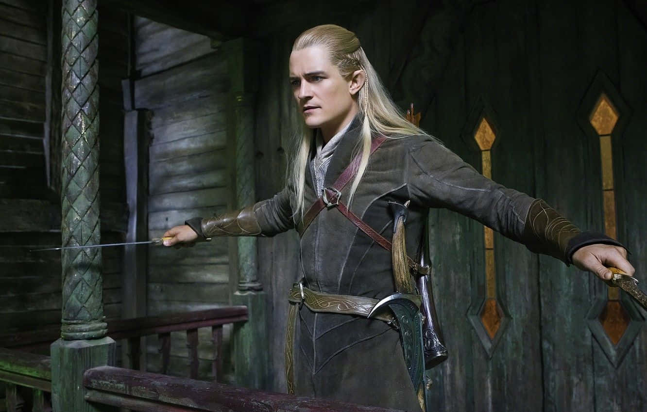 legolas 桌布 壁紙 — 長金髮的精靈戰士在質樸的木製大廳中手持劍和匕首，擺出架勢。