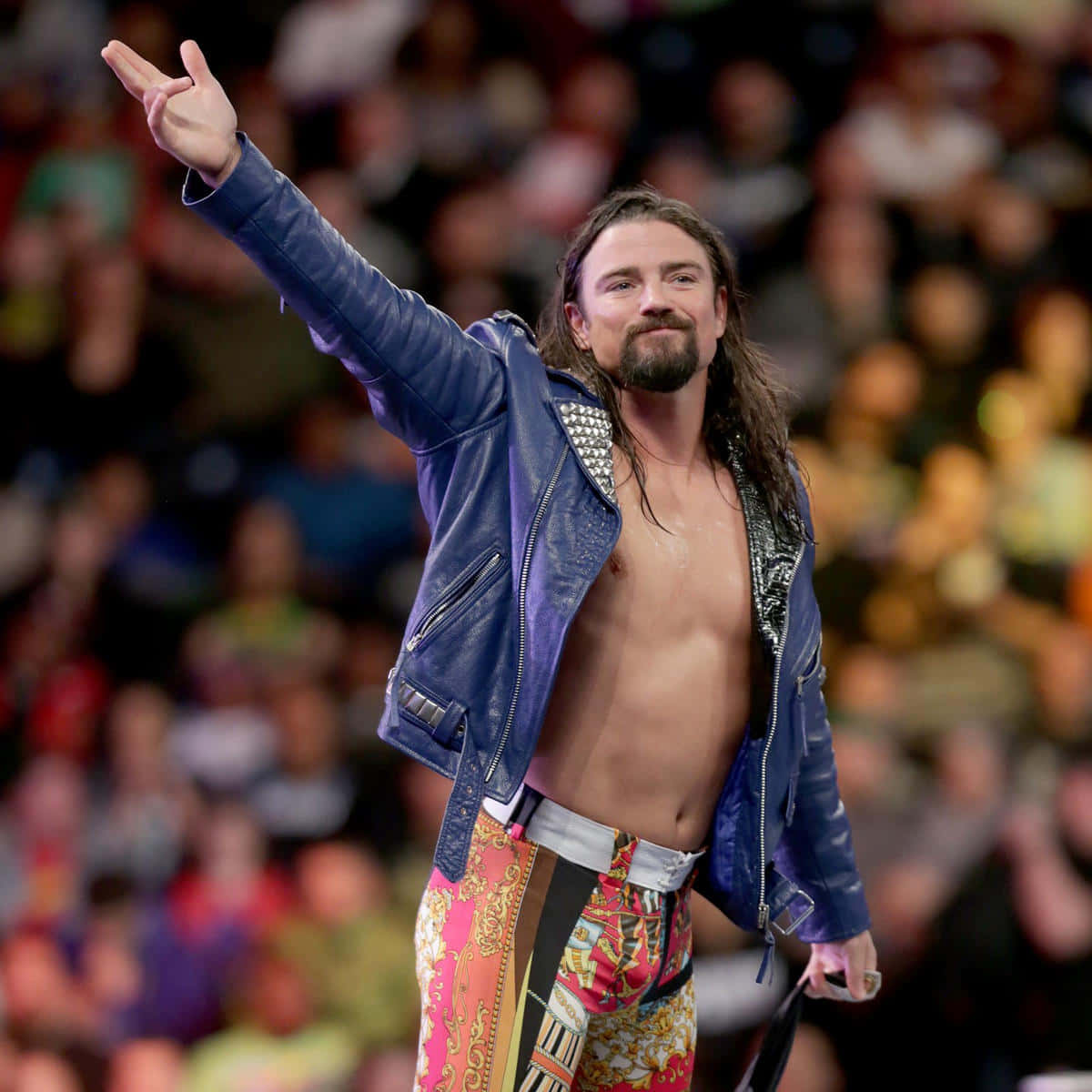 WWE 桌布 壁紙 — 長髮鬍鬚摔角手身穿藍色外套和圖案短褲，在場館燈光下向人群揮手。