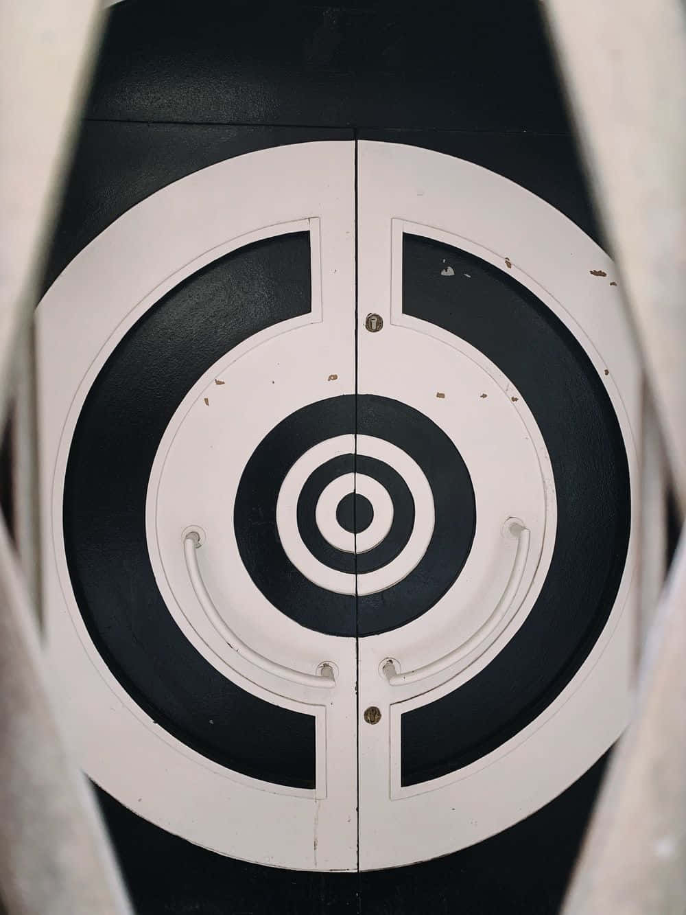 Shooting 桌布 壁紙 — 門上黑白圓形靶心設計的特寫，帶有可見磨損和兩個把手。