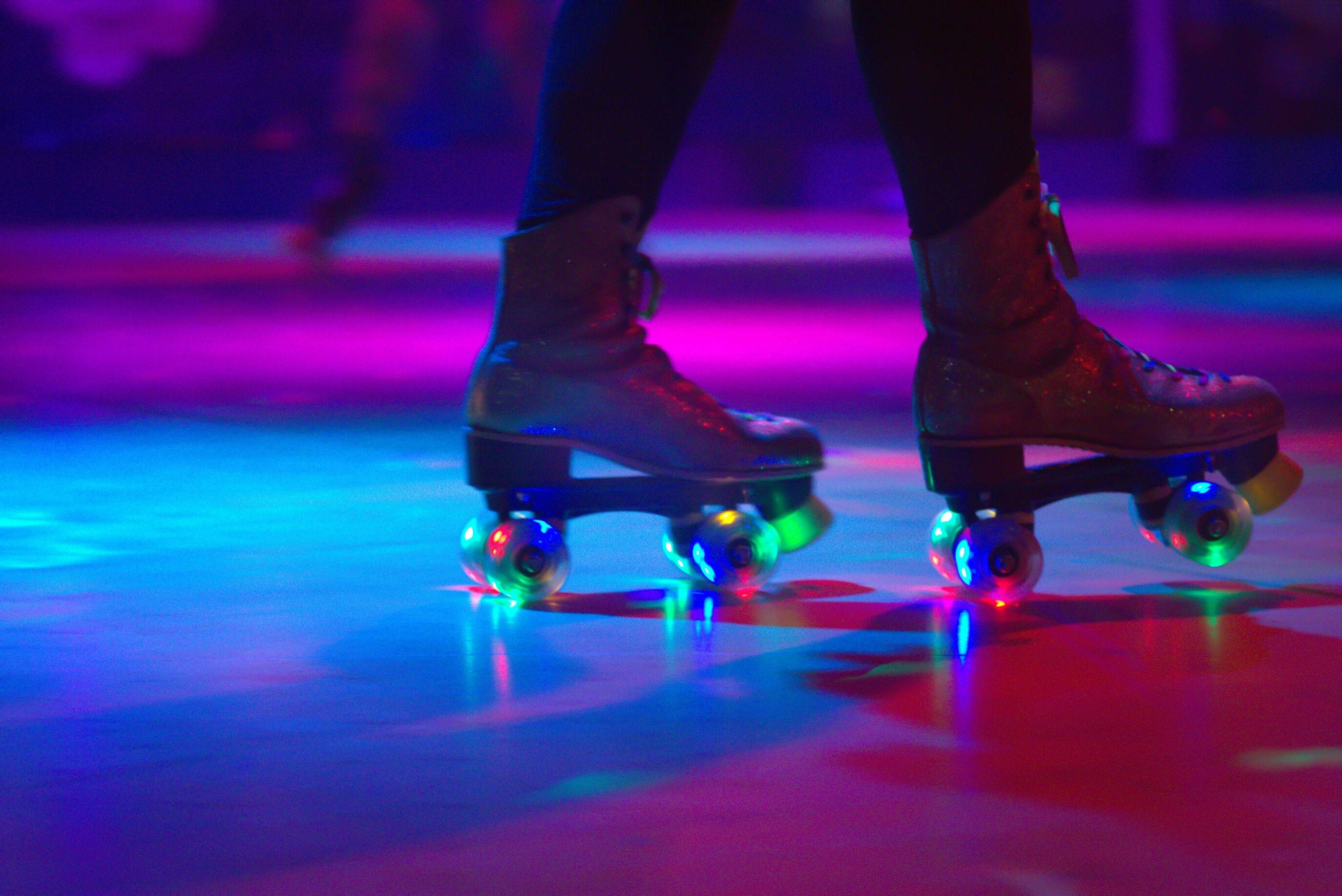 skating 桌布 壁紙 — 閃亮滾輪溜冰鞋的特寫，輪子發光，背景是充滿活力的霓虹燈溜冰場地板。