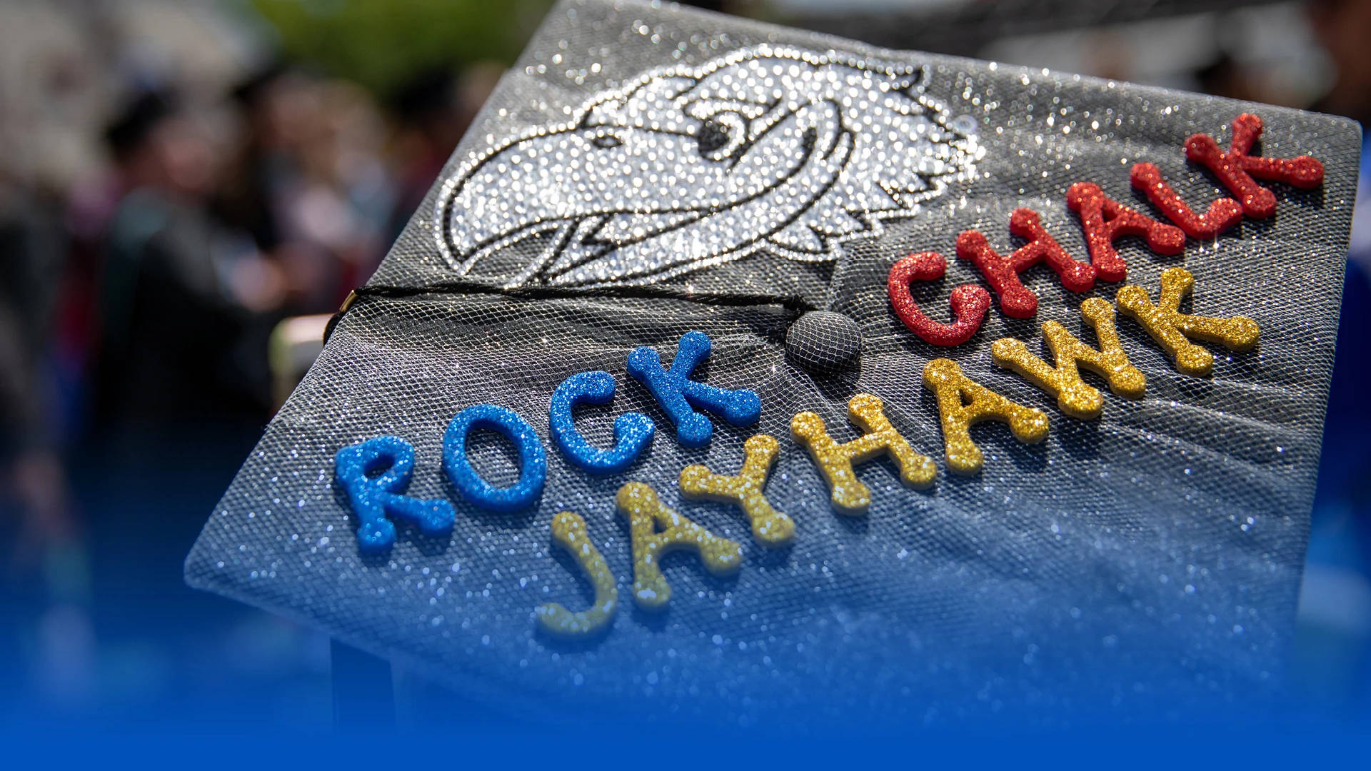 Graduation 桌布 壁紙 — 閃亮畢業帽的特寫，帶有Jayhawk吉祥物和色彩繽紛的凸字「Rock Jayhawk」。