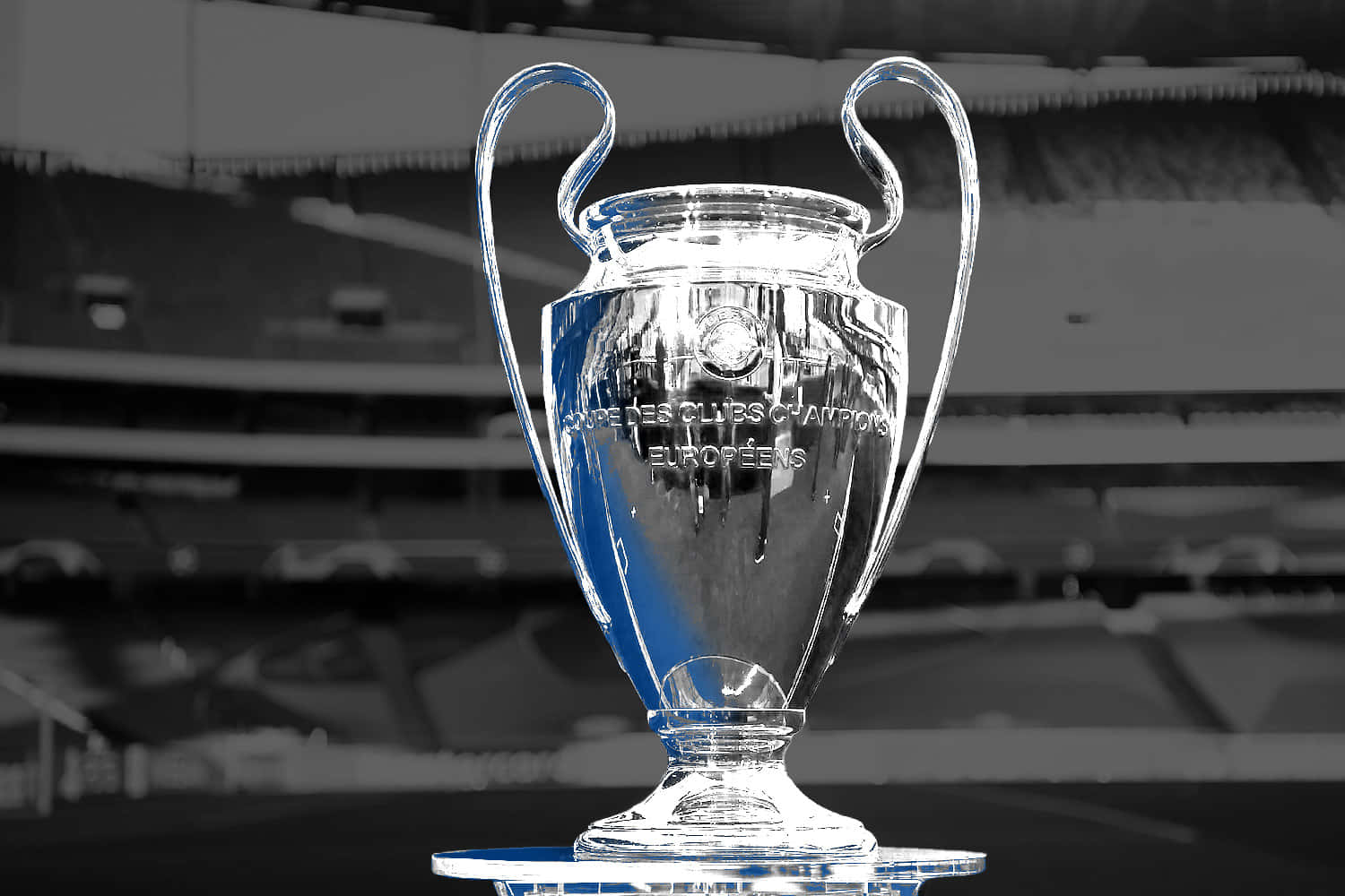 Champions League 桌布 壁紙 — 閃亮的 UEFA 歐冠獎盃在單色球場背景下，帶有選擇性的藍色亮點，清晰對焦。